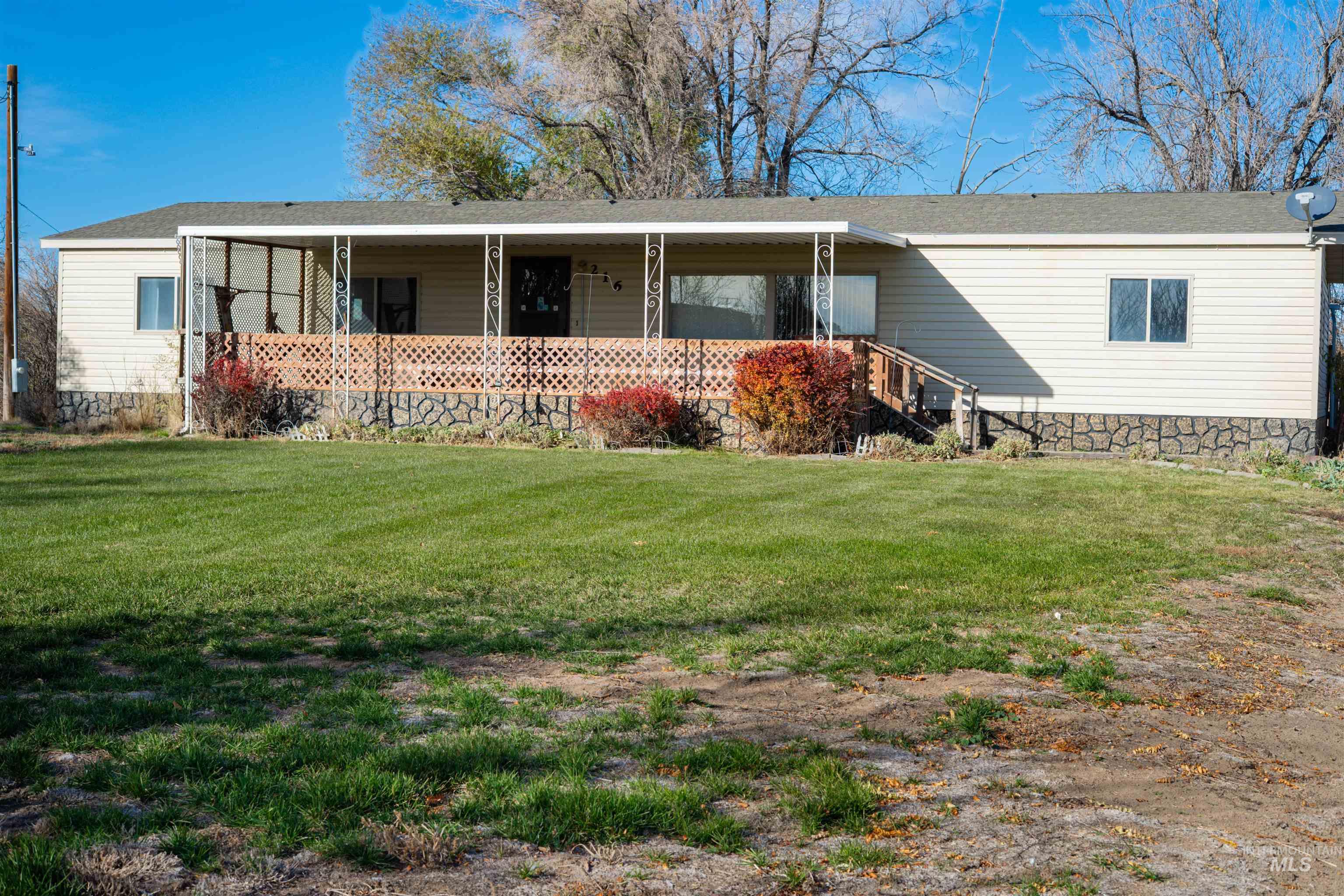 View of front of house with a front lawn, covered porch, and a shingled roof