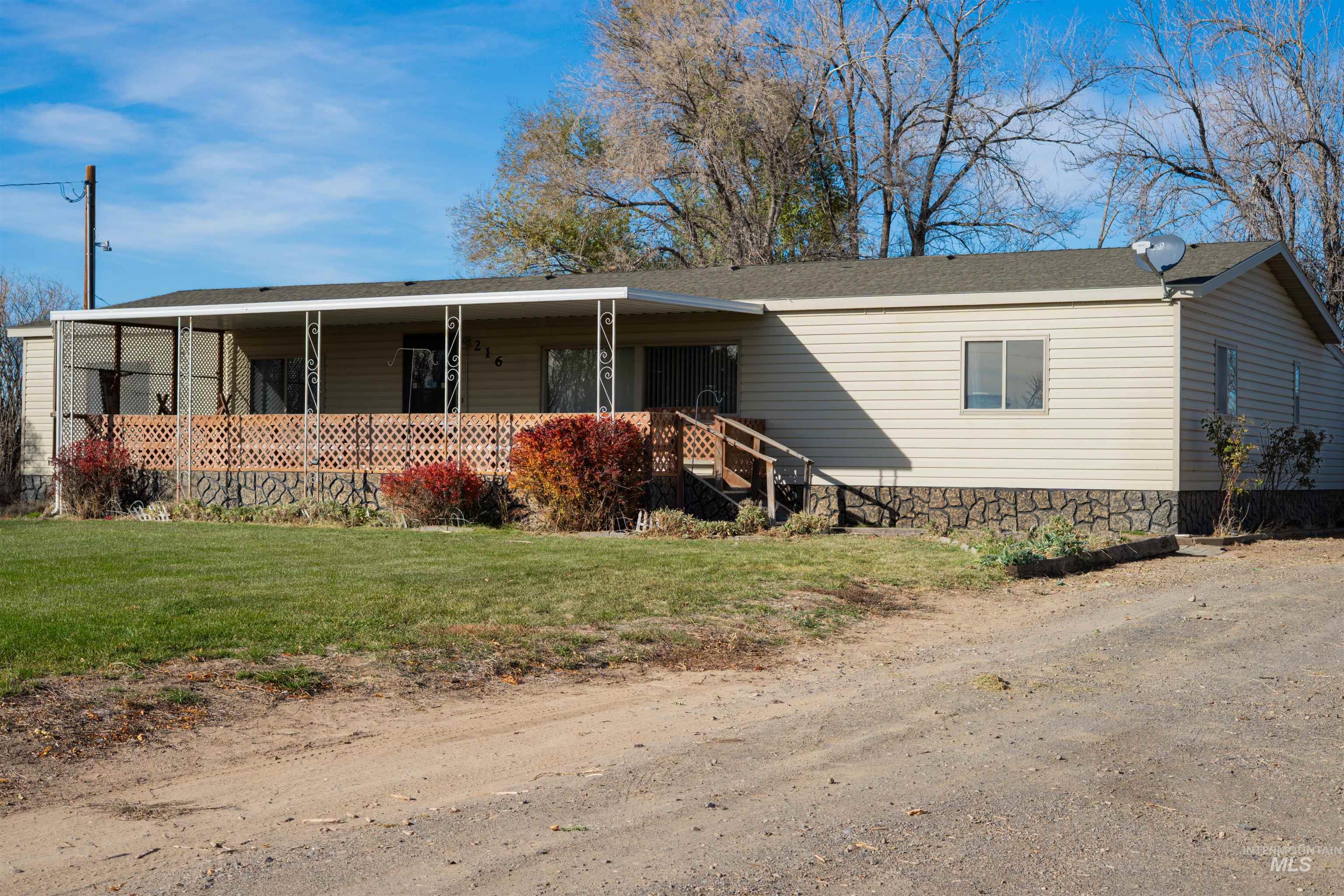 Manufactured / mobile home with covered porch, a front lawn, and roof with shingles