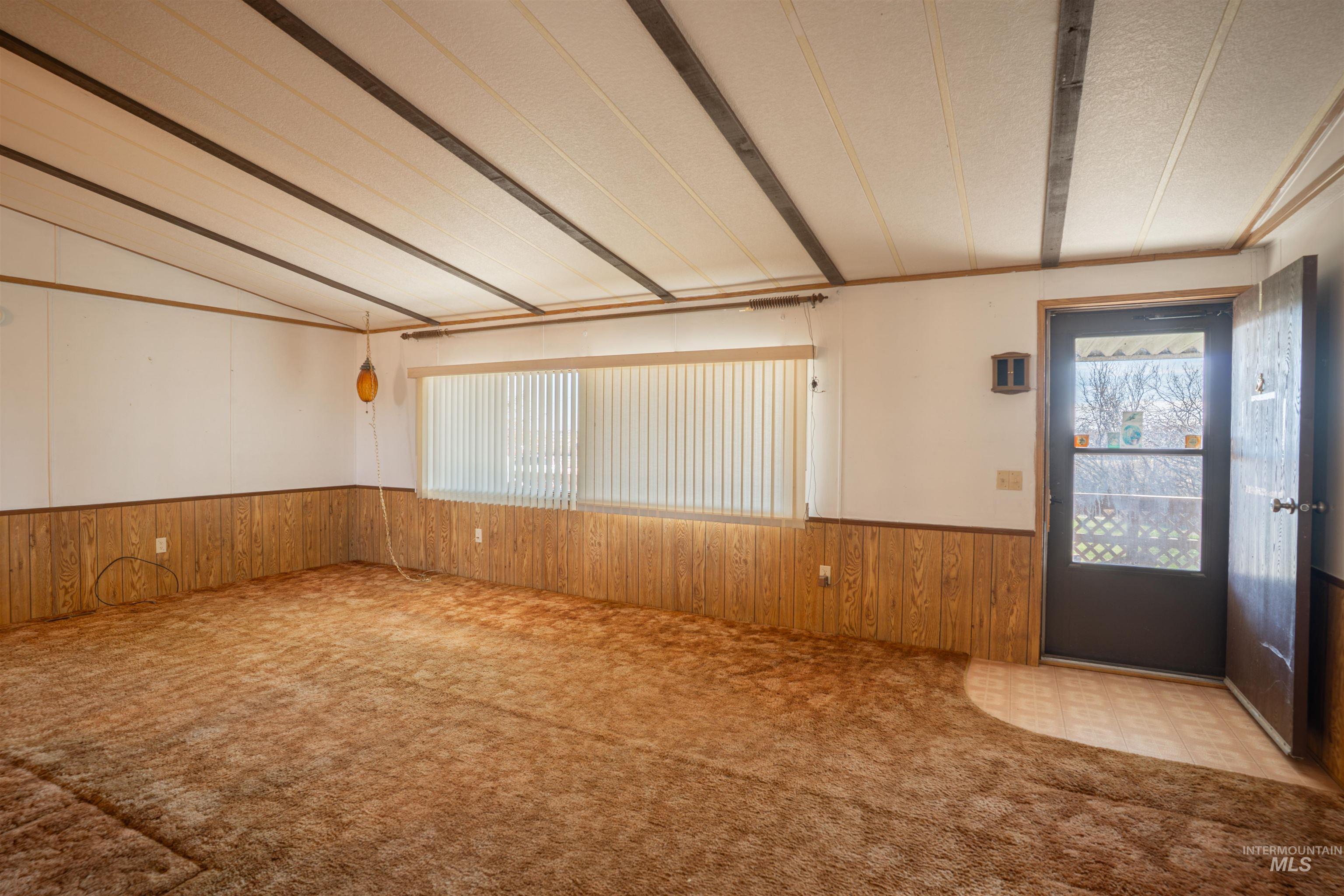 Foyer featuring wooden walls, a wainscoted wall, and carpet flooring
