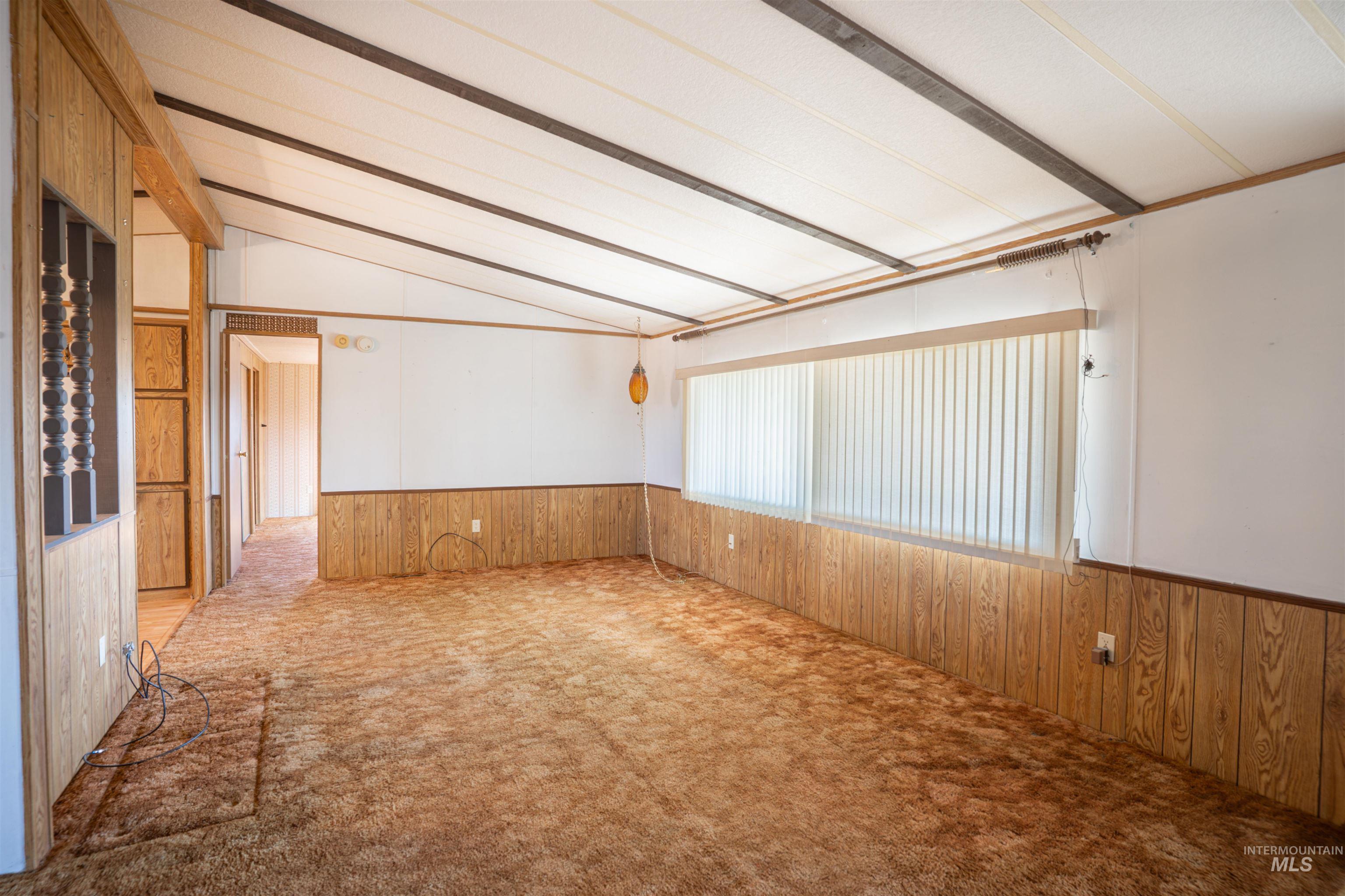 Carpeted empty room with wood walls and wainscoting