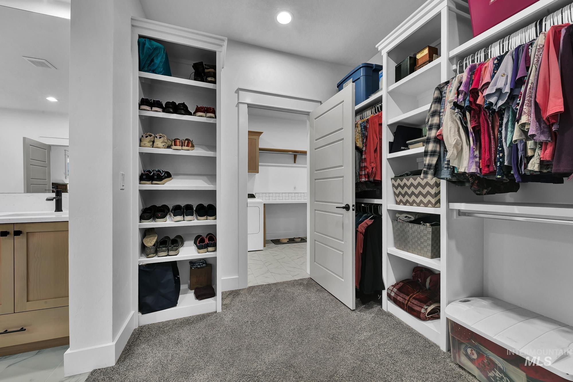 Spacious closet with light colored carpet and washer / clothes dryer