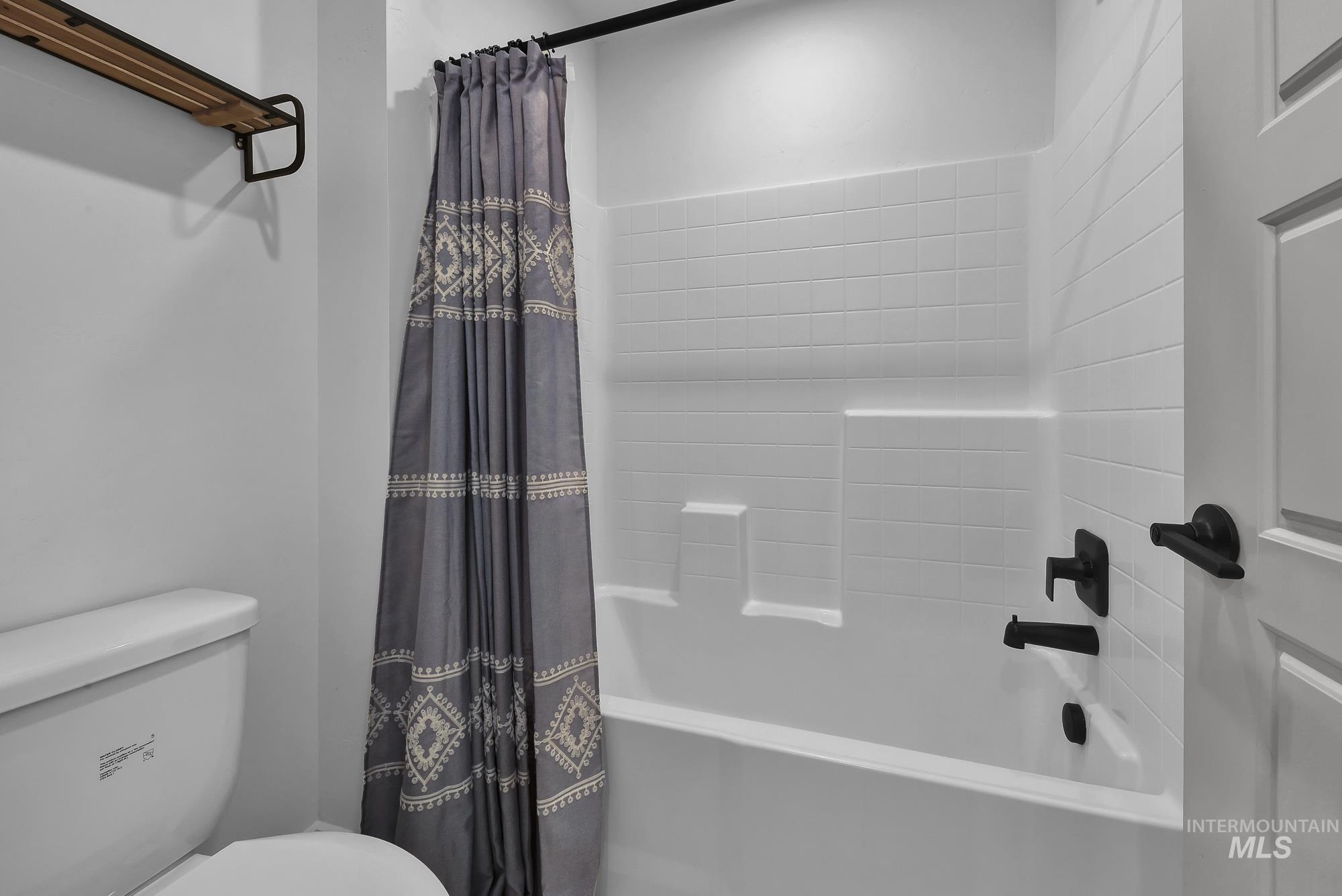 Full bath featuring shower / bath combo with shower curtain and toilet