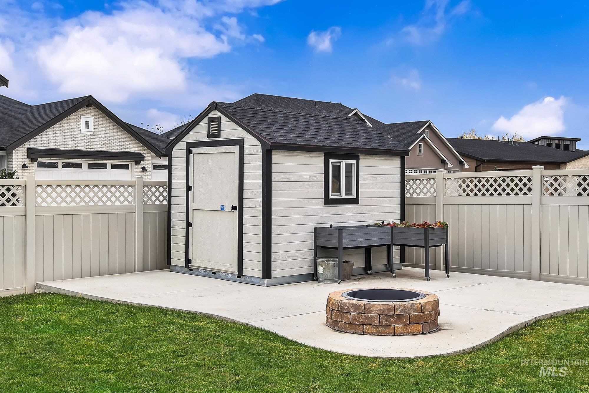 View of shed featuring an outdoor fire pit and a fenced backyard