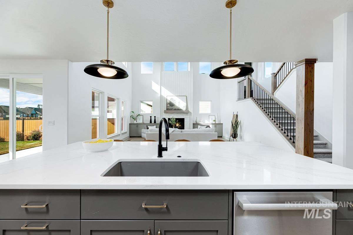 Kitchen featuring gray cabinetry, healthy amount of natural light, light stone counters, and a high ceiling