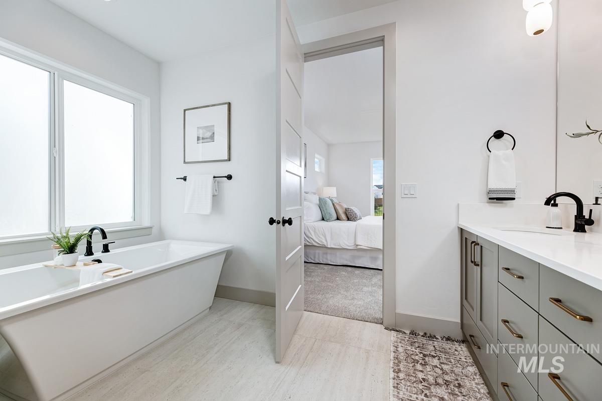Bathroom featuring a freestanding bath, vanity, ensuite bath, and light tile patterned floors