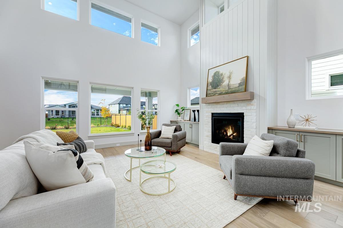 Living room with light wood finished floors, plenty of natural light, and a high ceiling