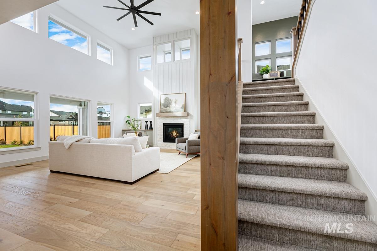 Stairs featuring a large fireplace, healthy amount of natural light, hardwood / wood-style flooring, a high ceiling, and recessed lighting