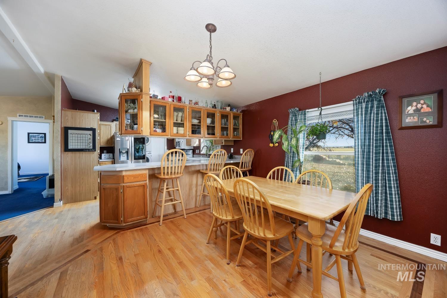Dining room with a chandelier, light wood-style flooring, and vaulted ceiling