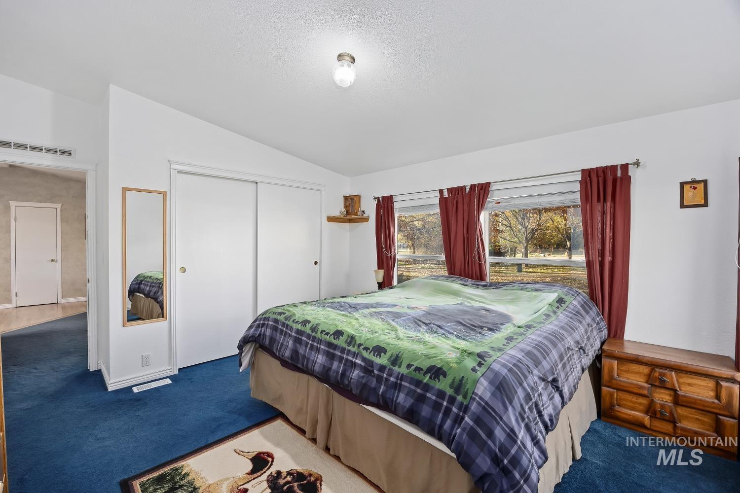 Bedroom featuring carpet floors, vaulted ceiling, a closet, and a textured ceiling