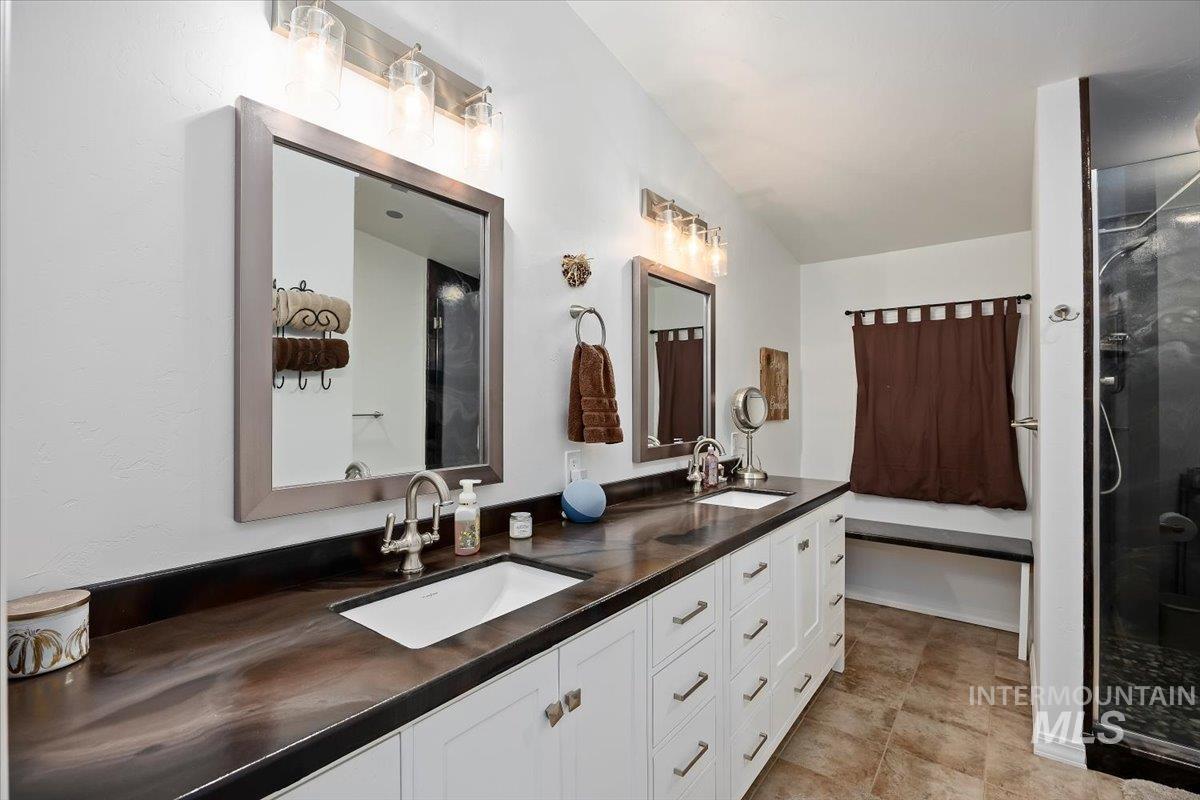 Bathroom featuring double vanity, a stall shower, and light tile patterned floors