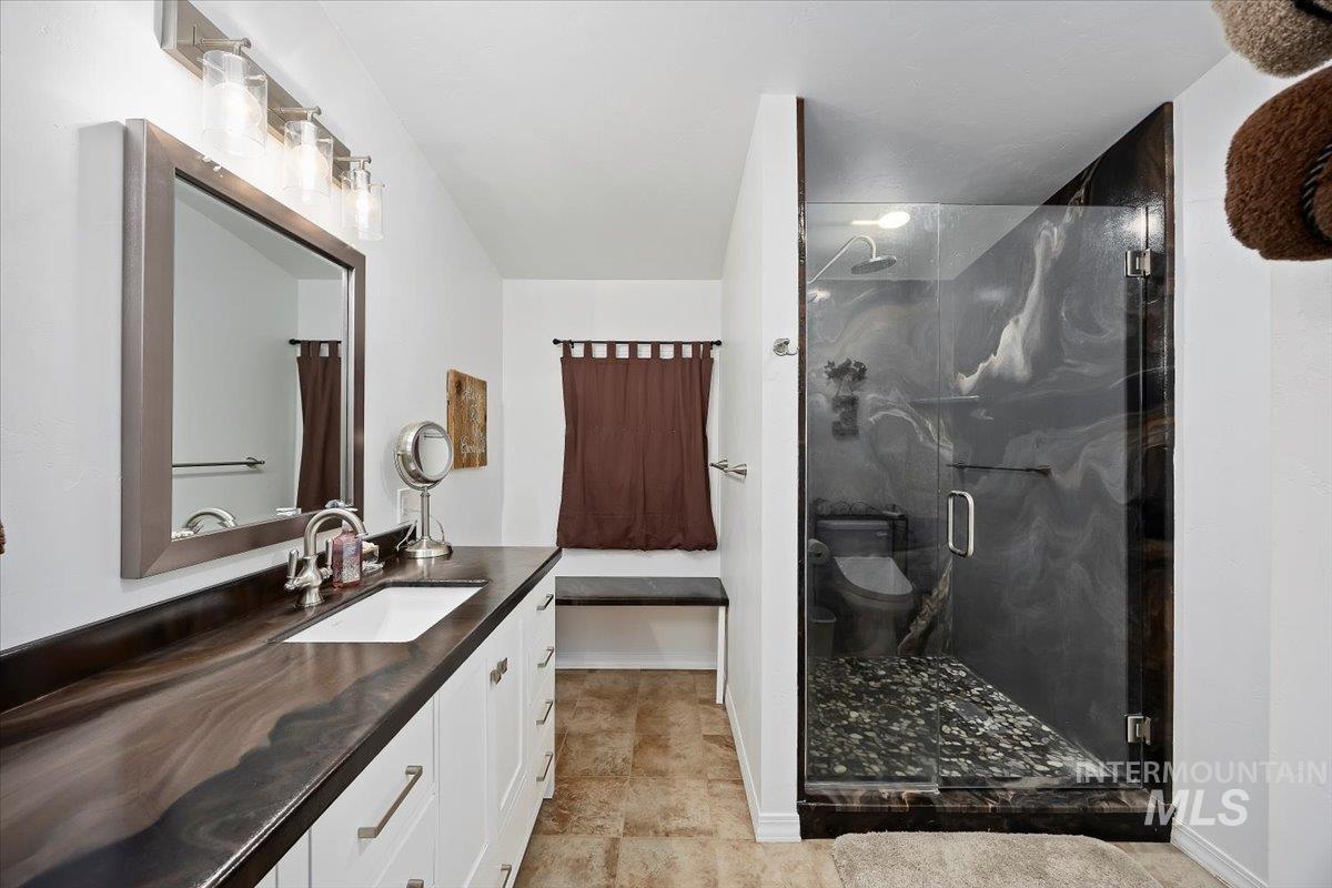 Bathroom featuring vanity, a marble finish shower, and light tile patterned floors