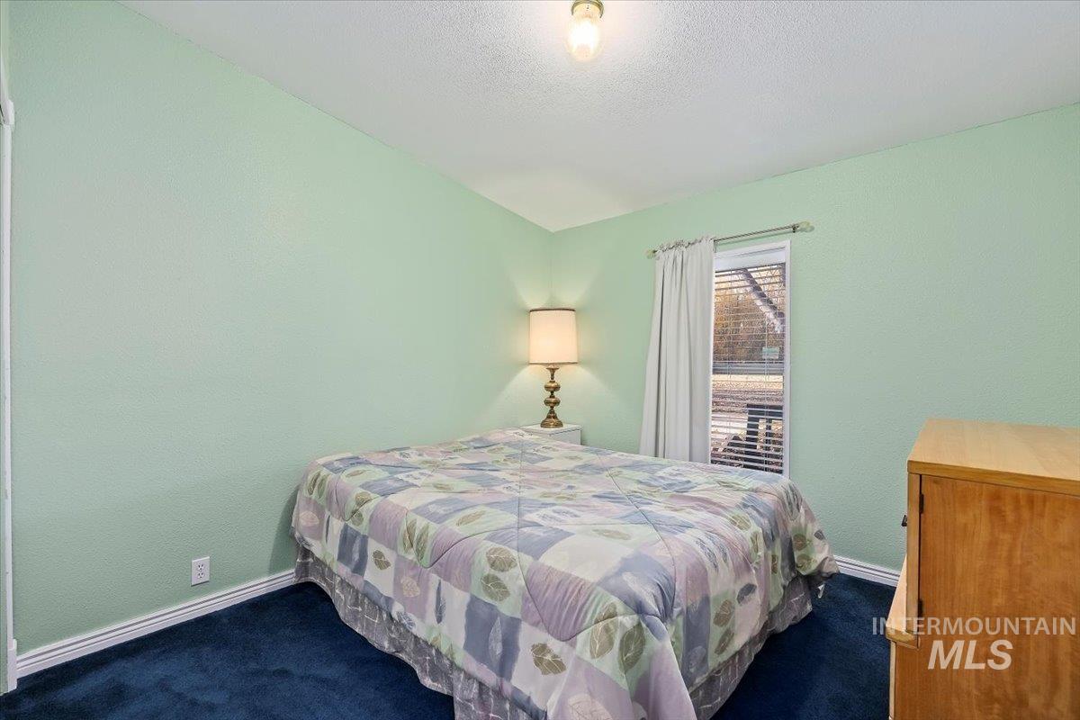 Carpeted bedroom featuring baseboards and a textured ceiling