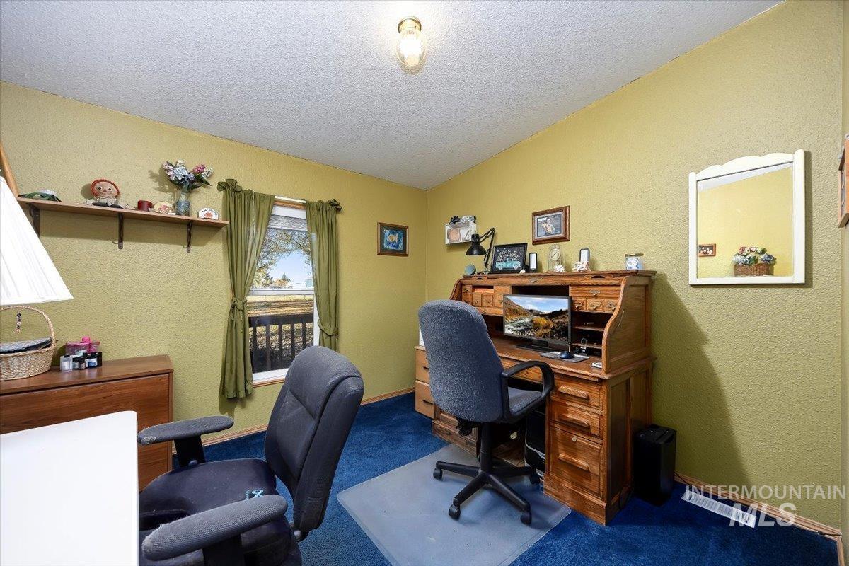 Carpeted office featuring a textured wall and a textured ceiling