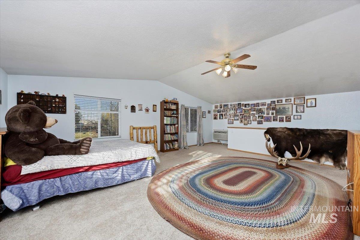 Bedroom with carpet, vaulted ceiling, a textured ceiling, and a ceiling fan