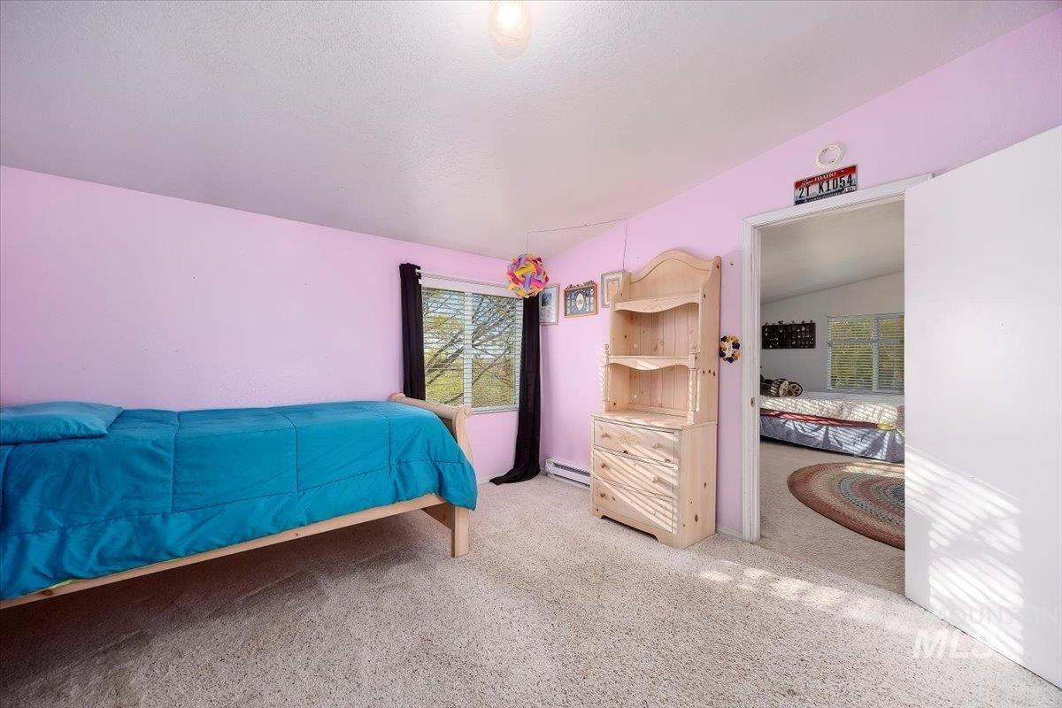 Carpeted bedroom with lofted ceiling and a baseboard heating unit