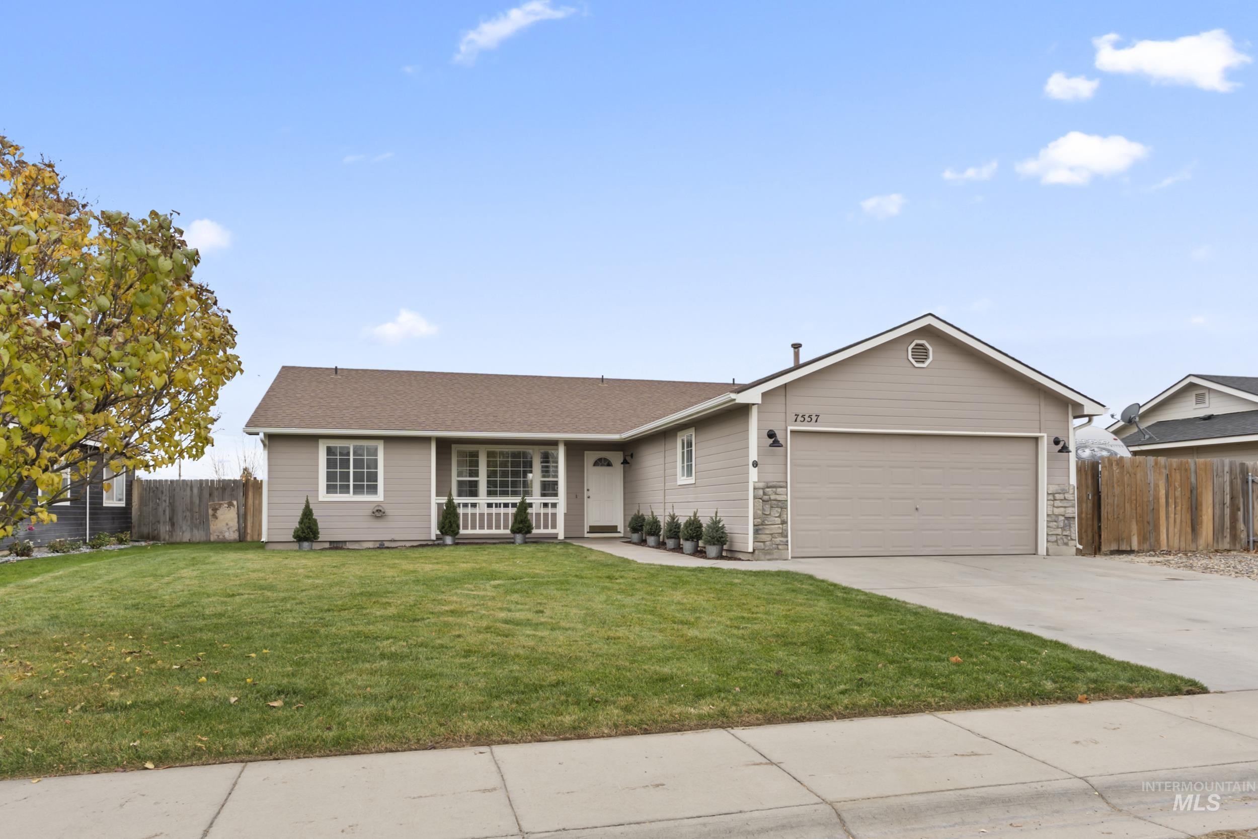 Ranch-style home featuring concrete driveway, a garage, and stone siding