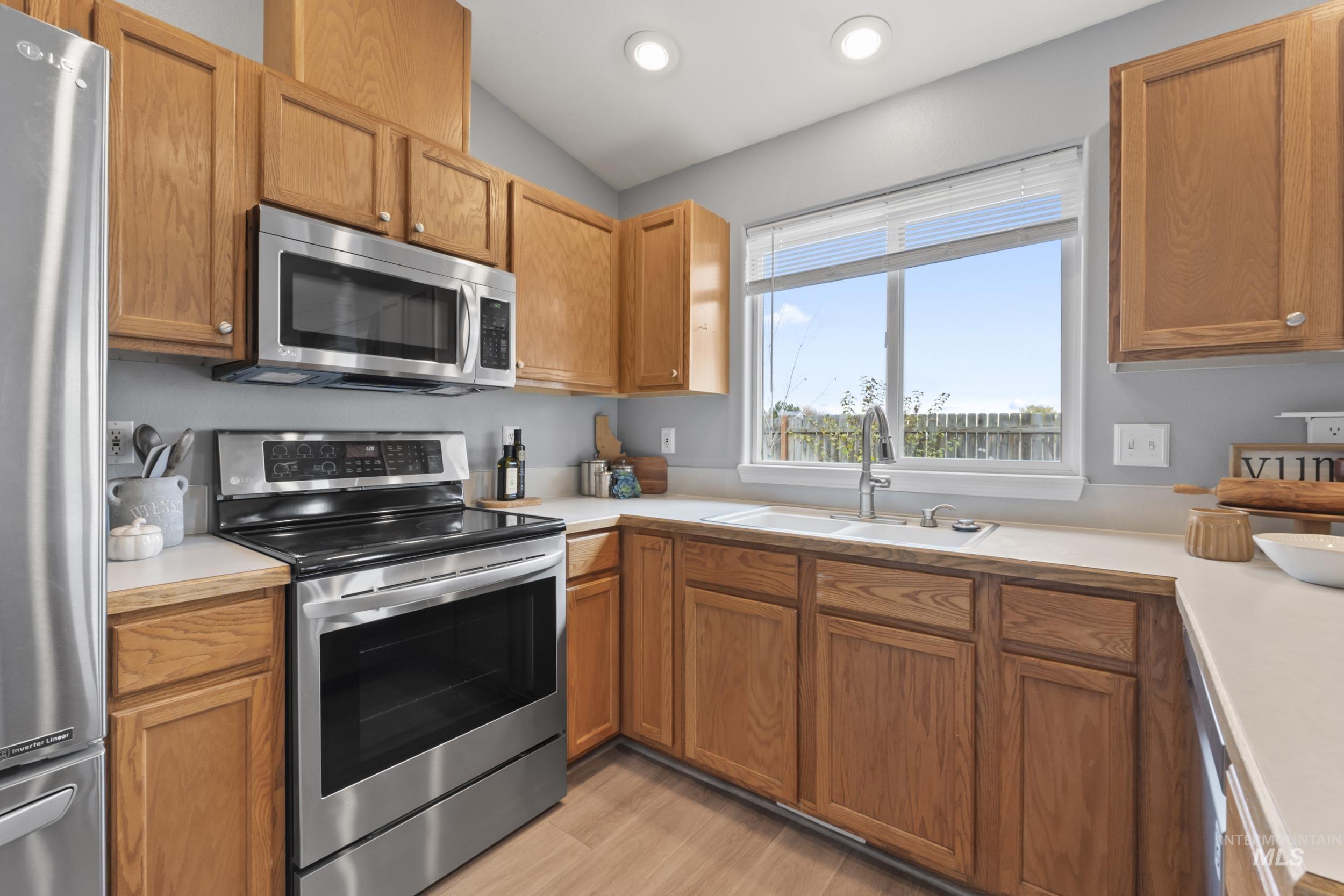 Kitchen with appliances with stainless steel finishes, light countertops, light wood-style floors, brown cabinets, and recessed lighting