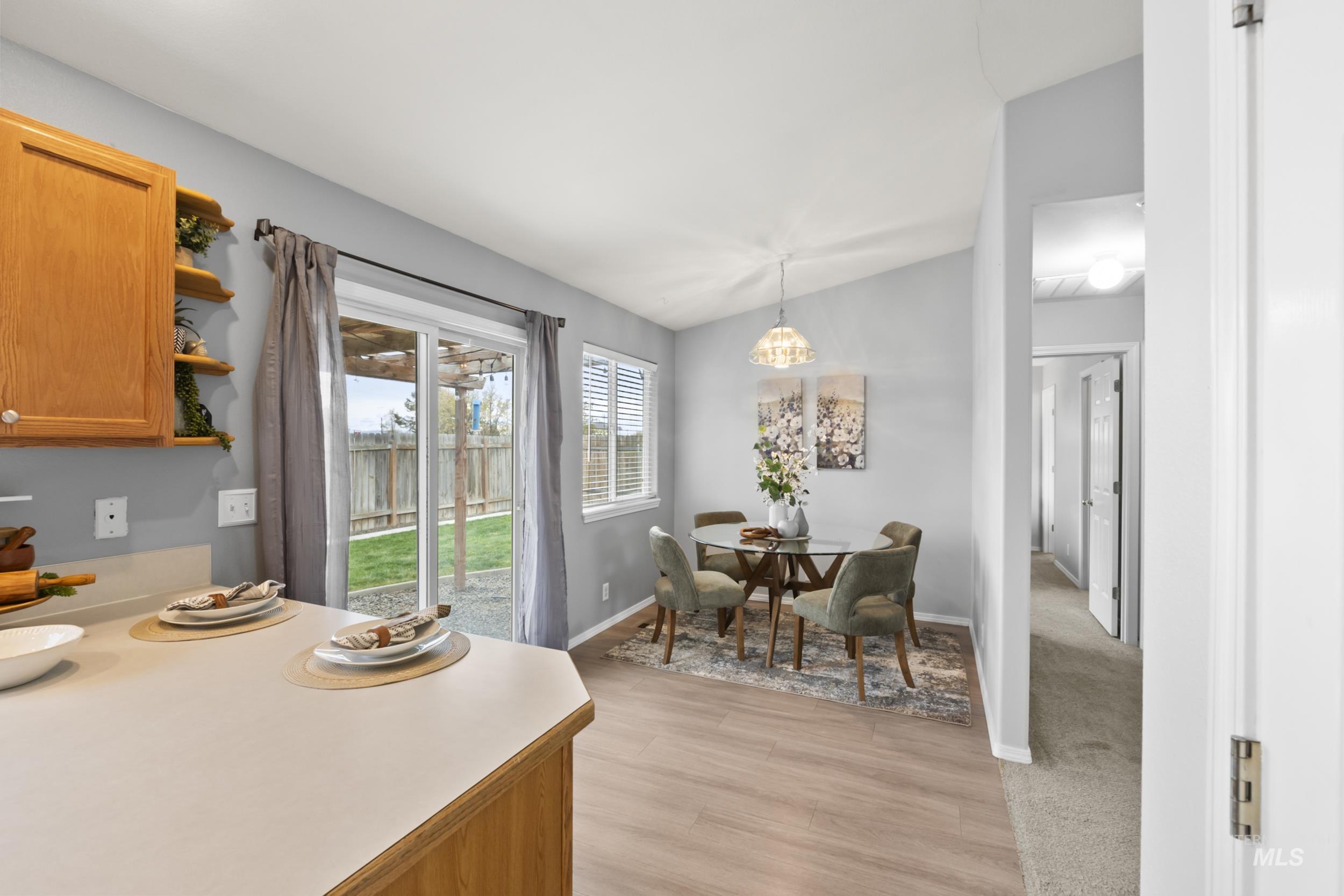 Dining area with light wood-style floors and lofted ceiling