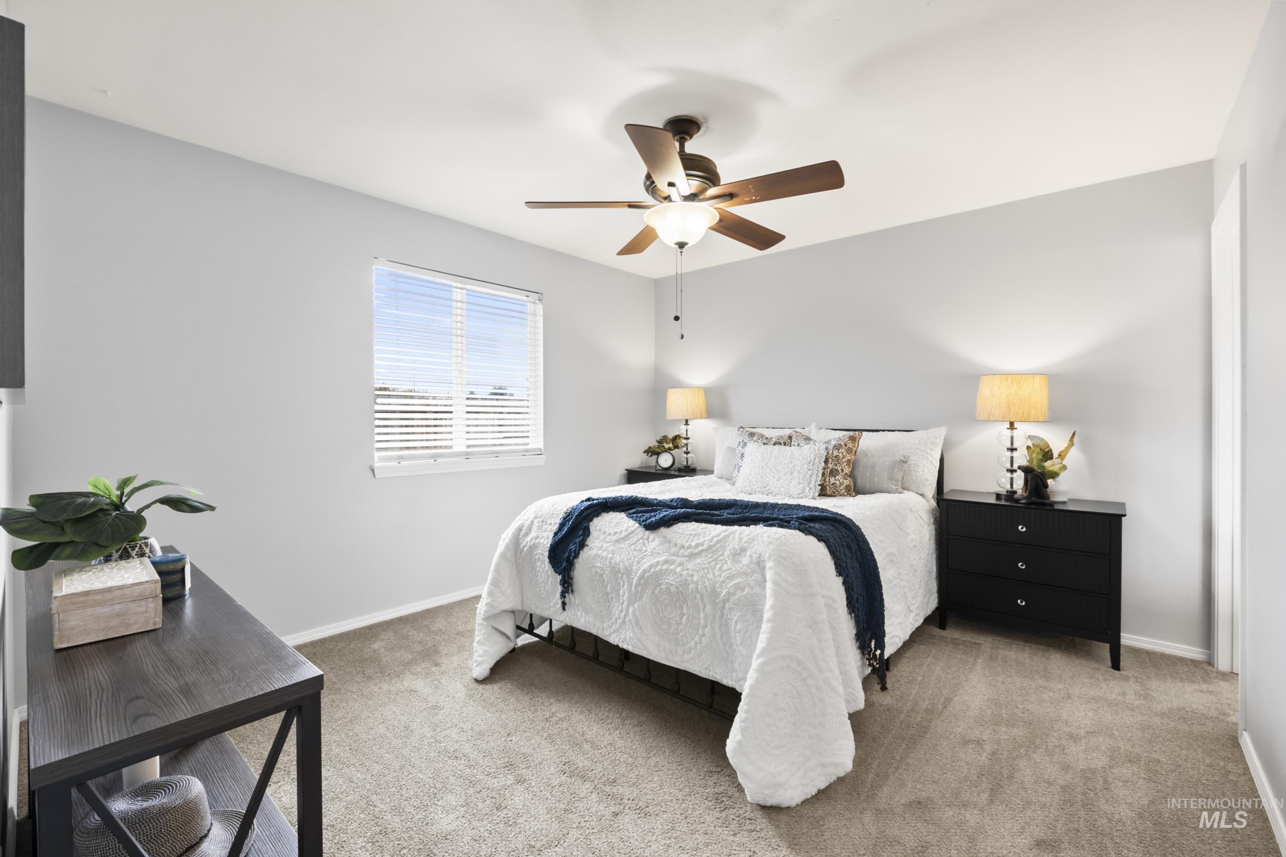 Carpeted bedroom featuring ceiling fan and baseboards