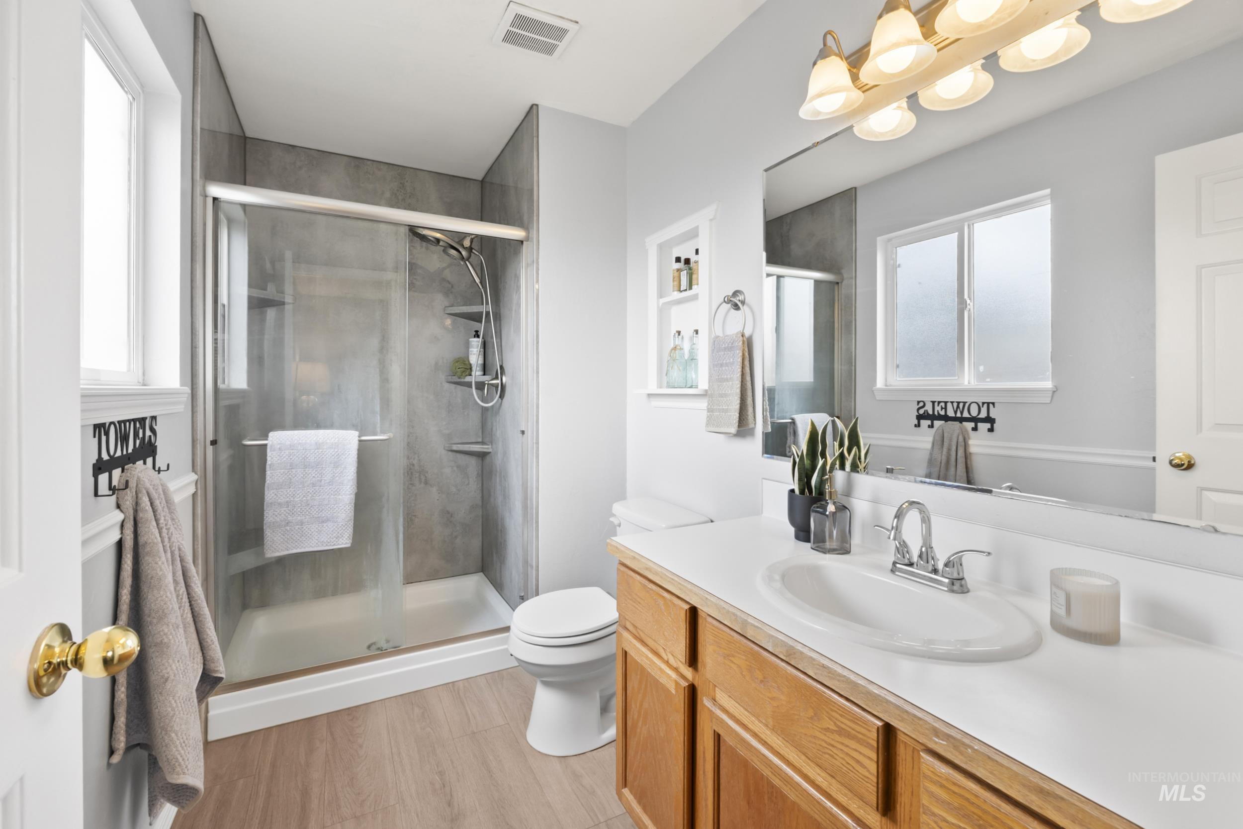 Full bath with vanity, light wood finished floors, and a stall shower