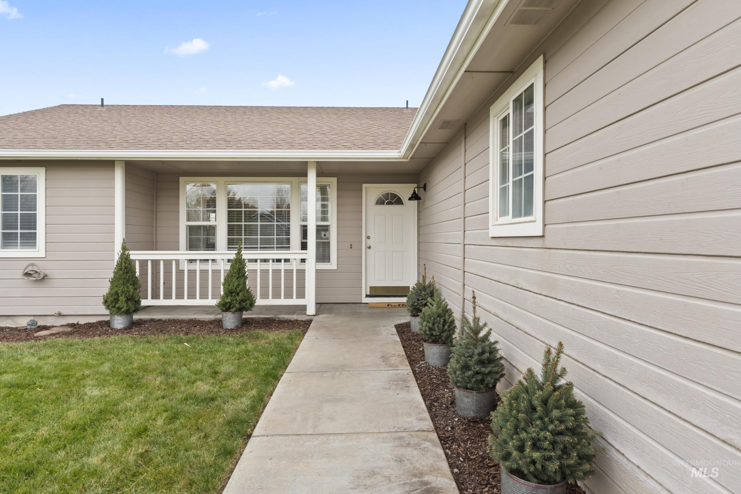 View of exterior entry featuring a yard, roof with shingles, and a porch