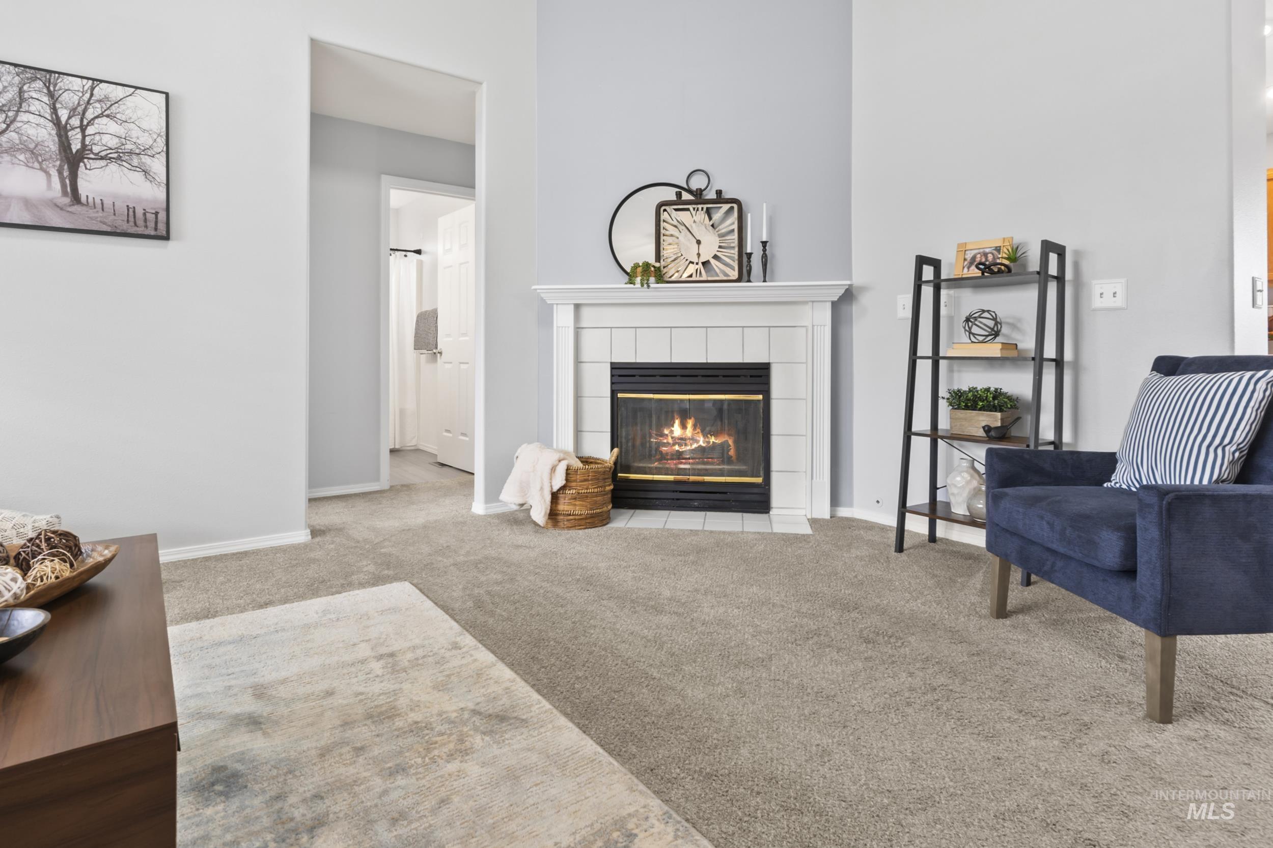 Carpeted living area featuring a tiled fireplace and baseboards