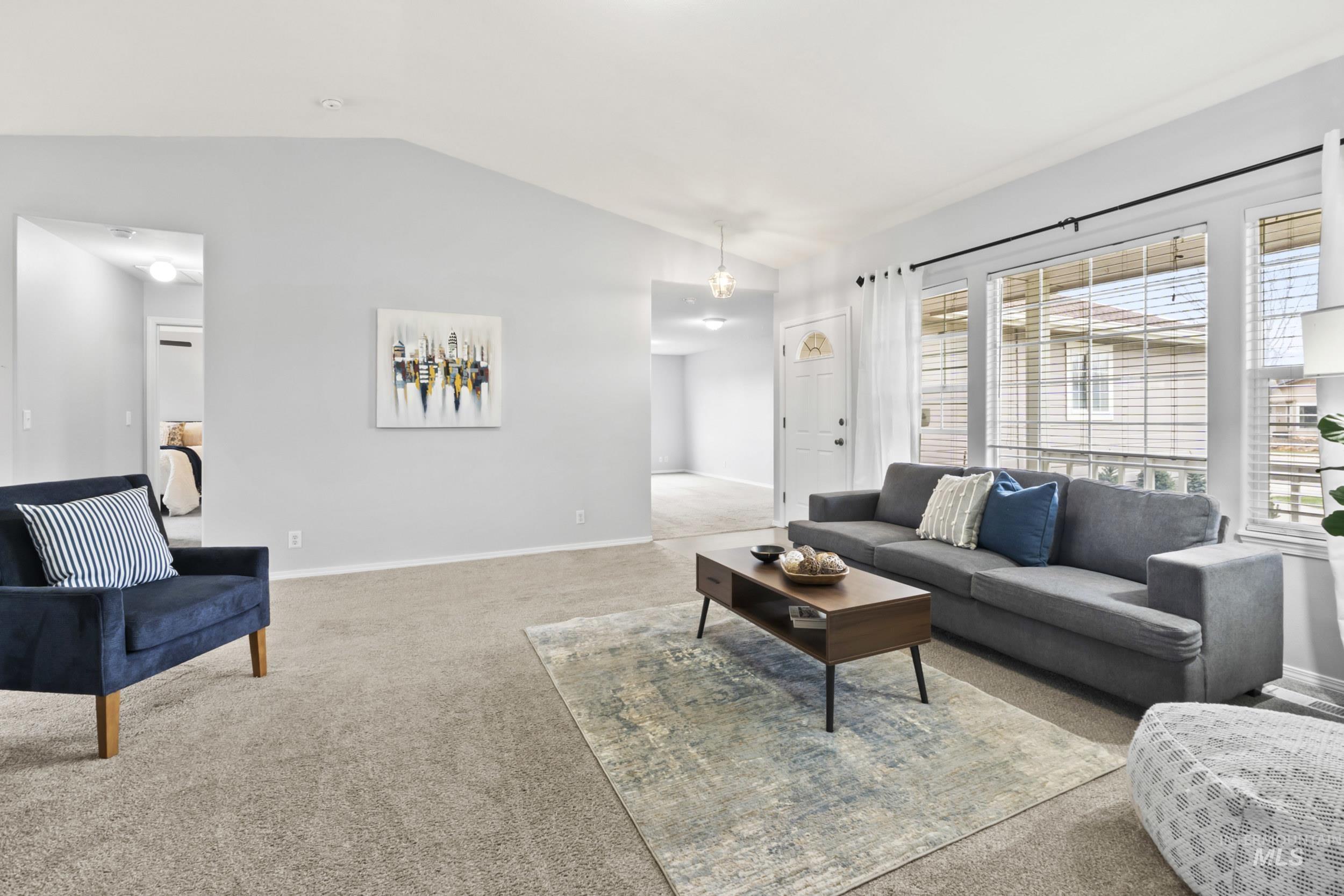Carpeted living room featuring lofted ceiling and baseboards