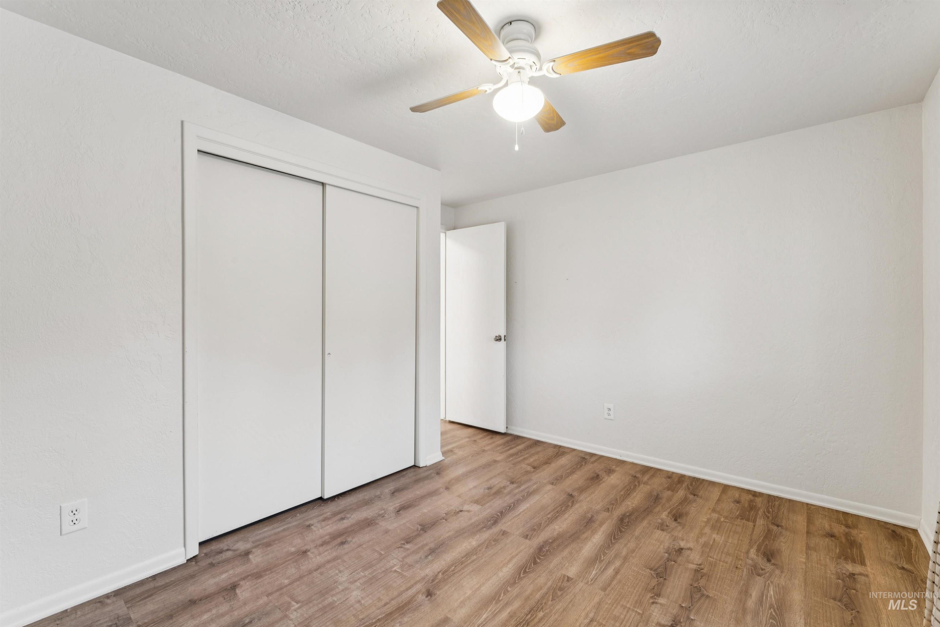 Unfurnished bedroom with wood finished floors, ceiling fan, and a closet