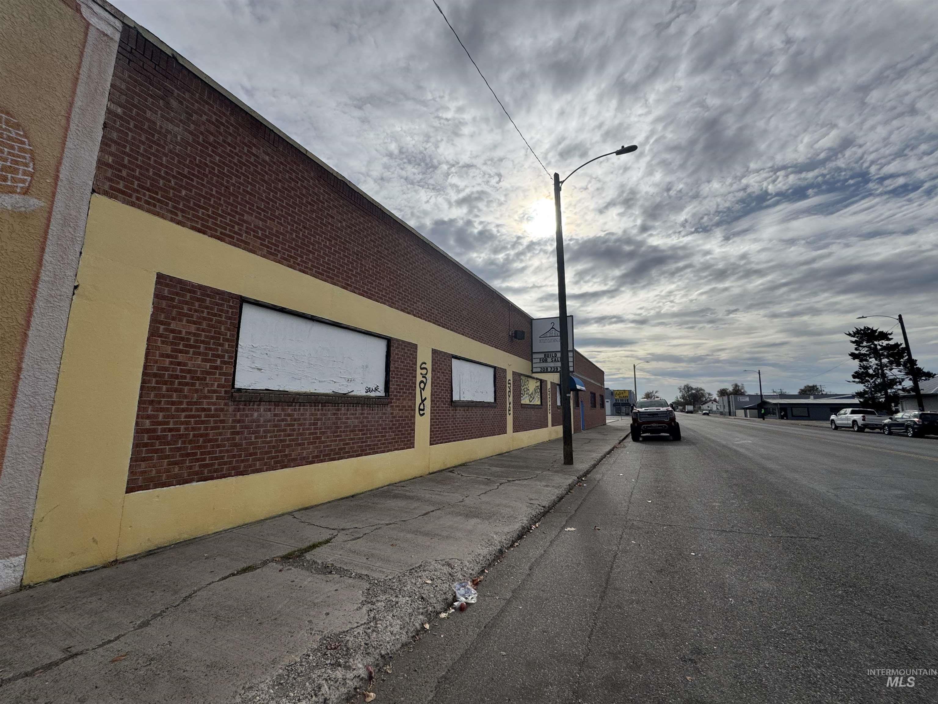 View of asphalt road featuring sidewalks, curbs, and street lights