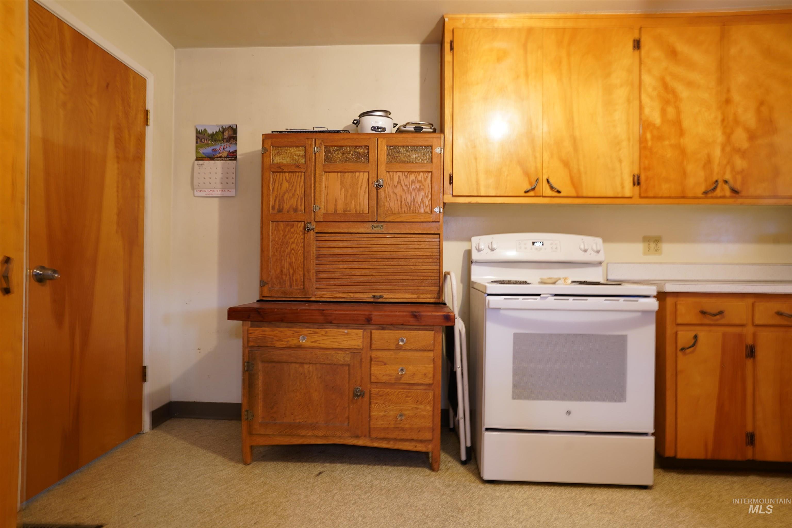 Kitchen with electric range, brown cabinets, light countertops