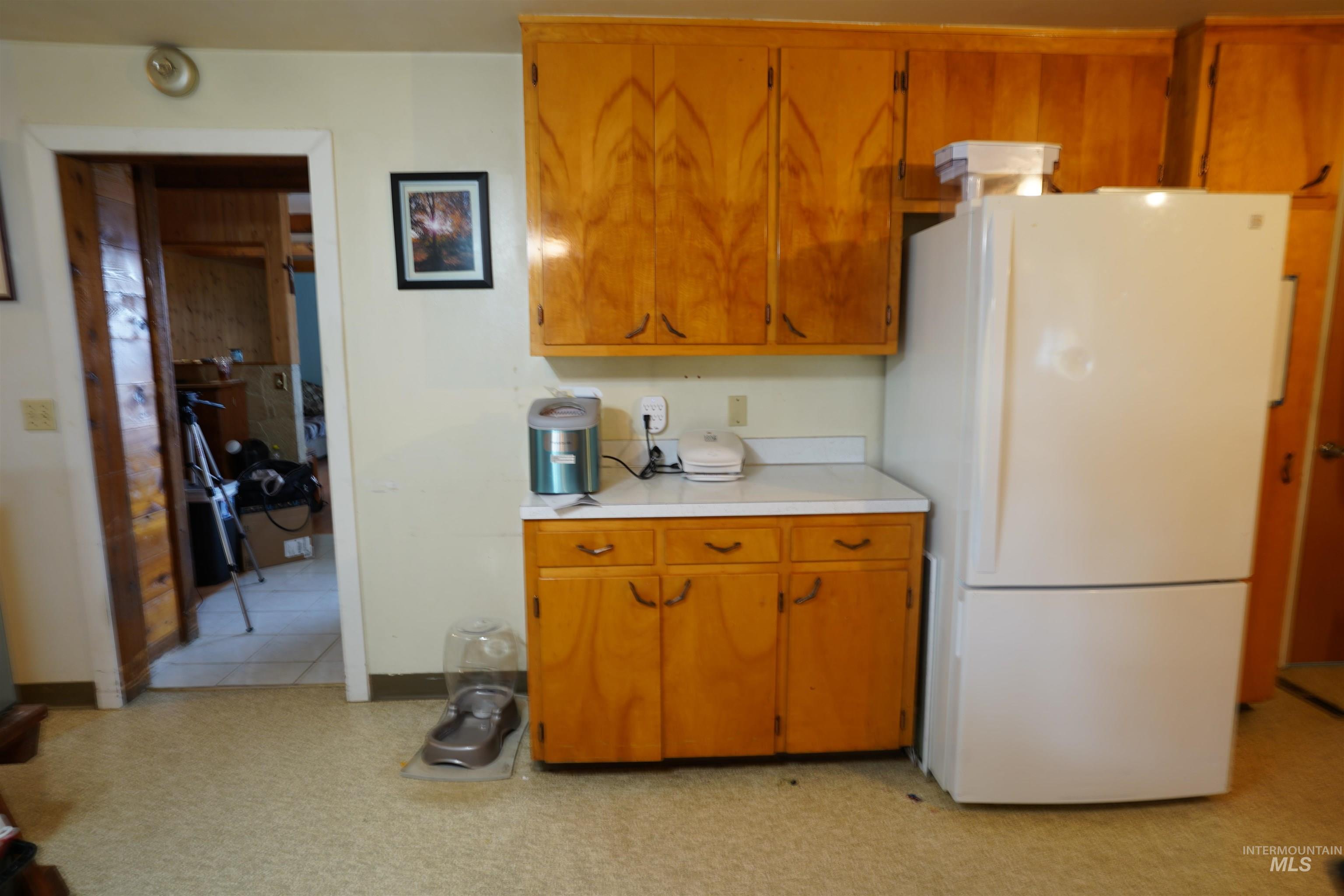 Kitchen featuring freestanding refrigerator, light countertops, and brown cabinetry