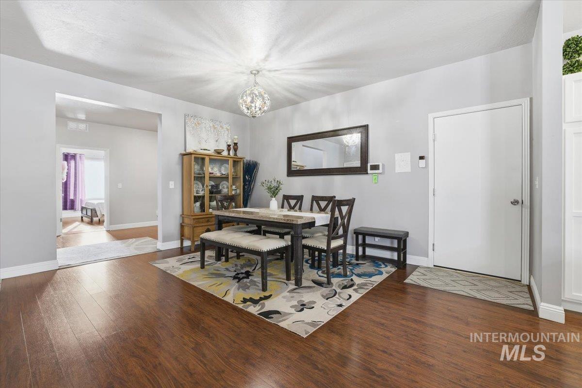 Dining room with dark wood-style flooring and a chandelier