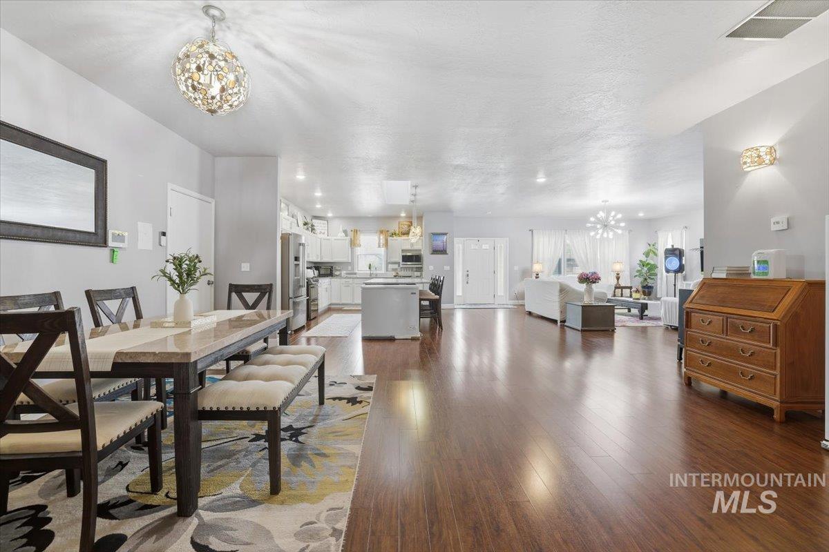 Dining space featuring a chandelier, dark wood-type flooring, recessed lighting, and a textured ceiling