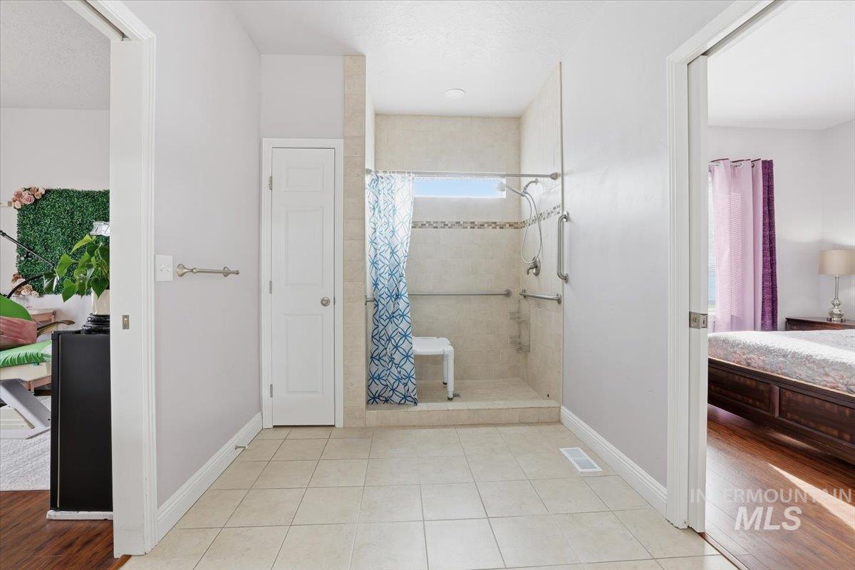Ensuite bathroom featuring light tile patterned flooring and tiled shower