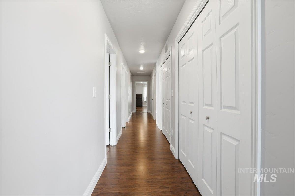 Hall with dark wood-style flooring and baseboards