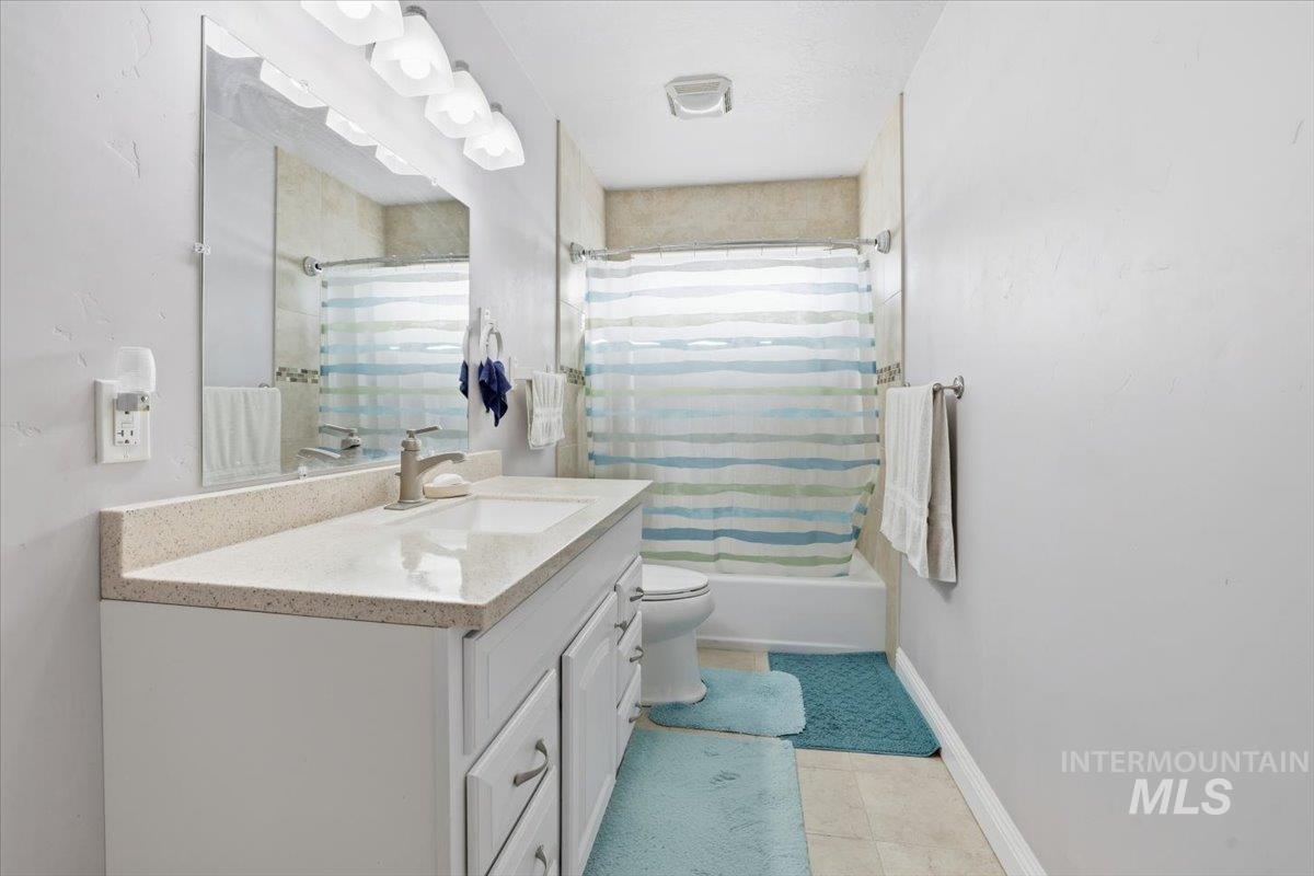 Bathroom featuring vanity, shower / tub combo with curtain, and light tile patterned floors