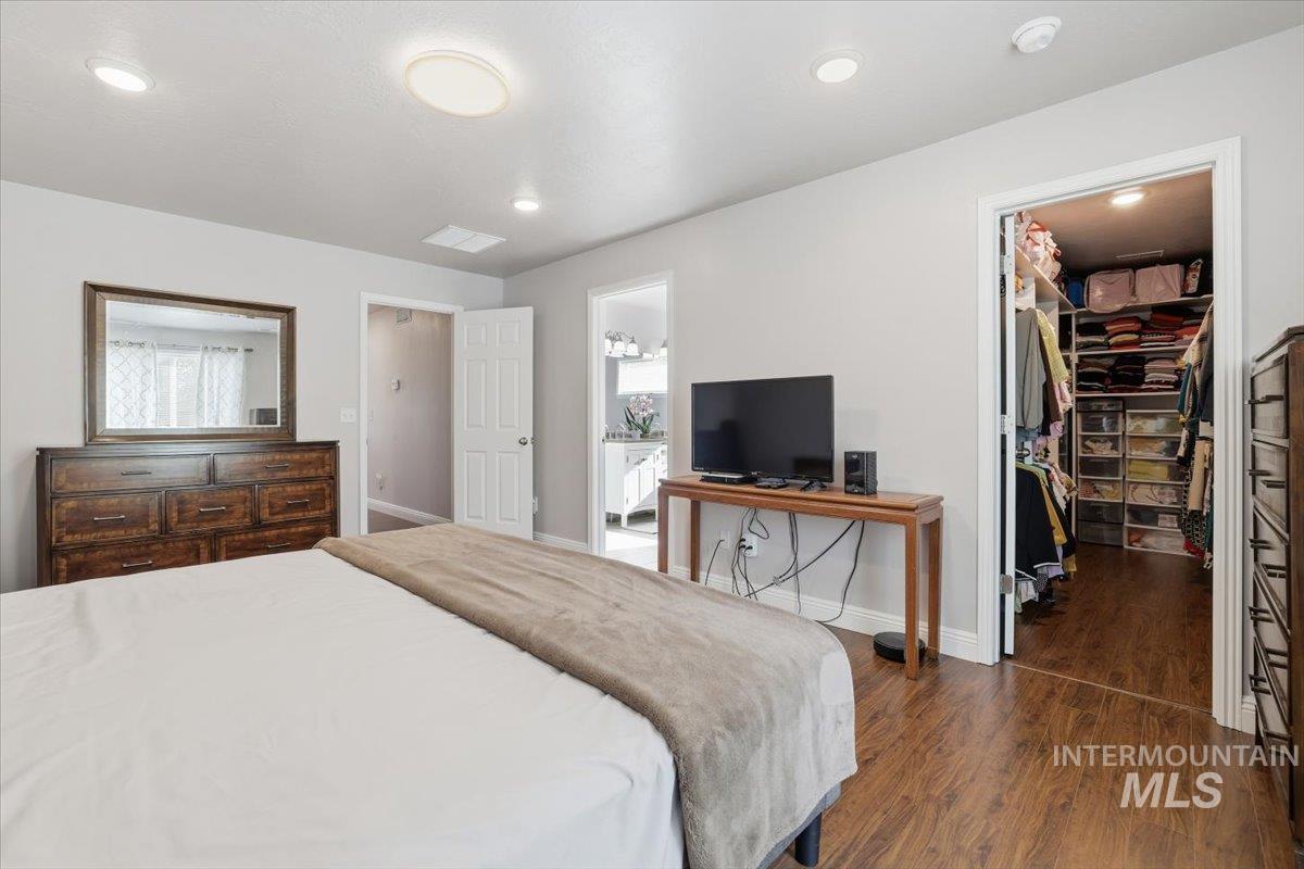 Bedroom featuring a walk in closet, dark wood-style flooring, and recessed lighting
