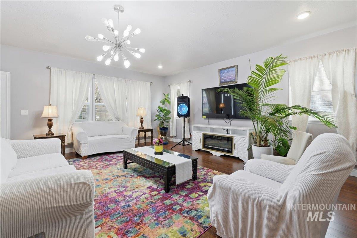 Living room featuring wood finished floors, a glass covered fireplace, and a chandelier