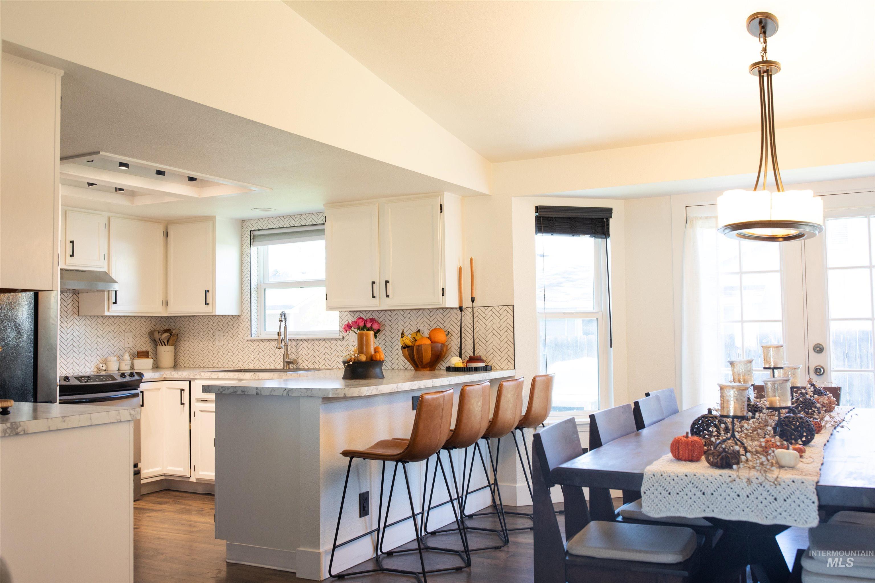 Kitchen with decorative backsplash, light countertops and a breakfast bar