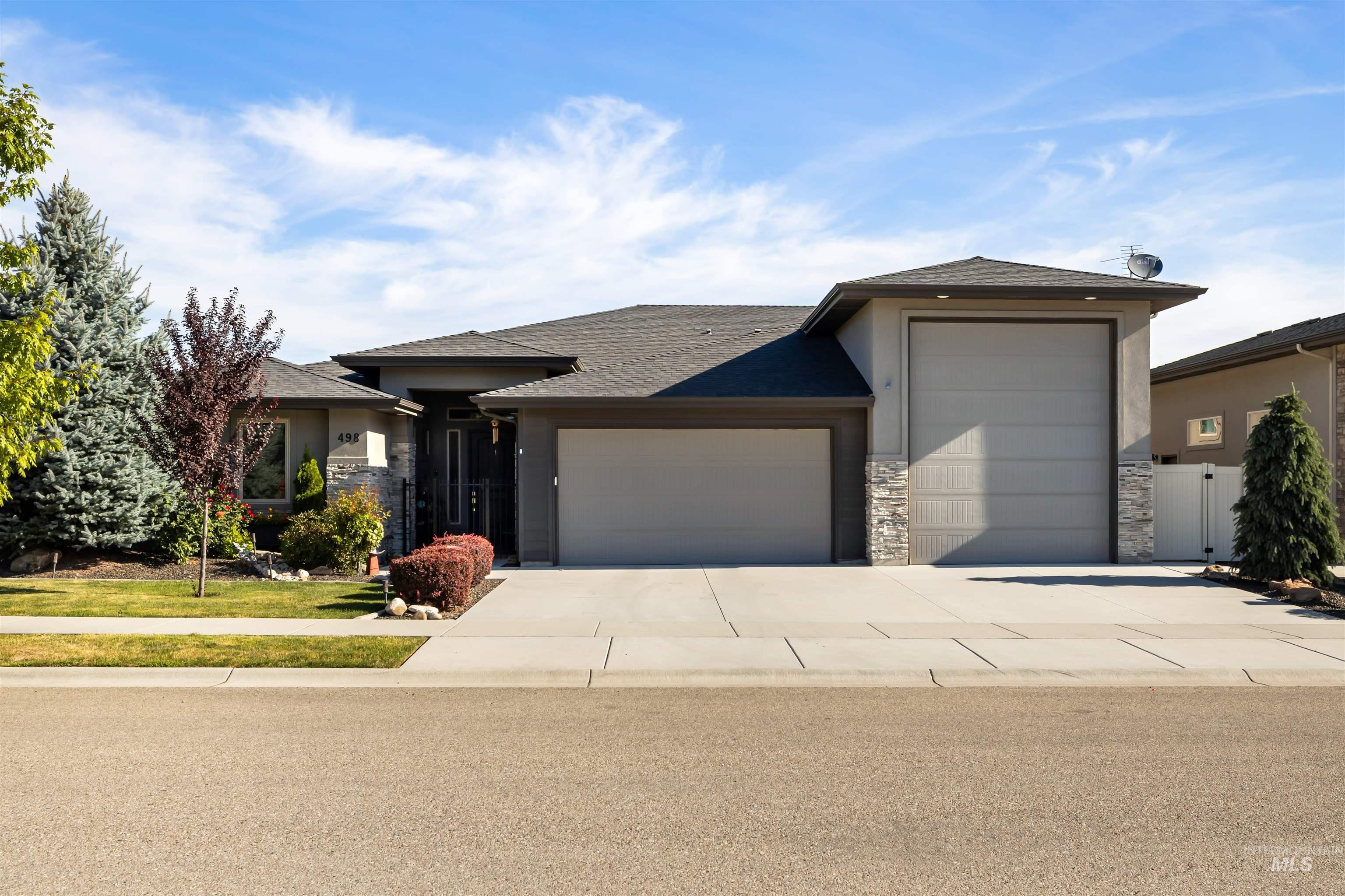 Prairie-style house with stone siding, a garage, a shingled roof, driveway, and stucco siding
