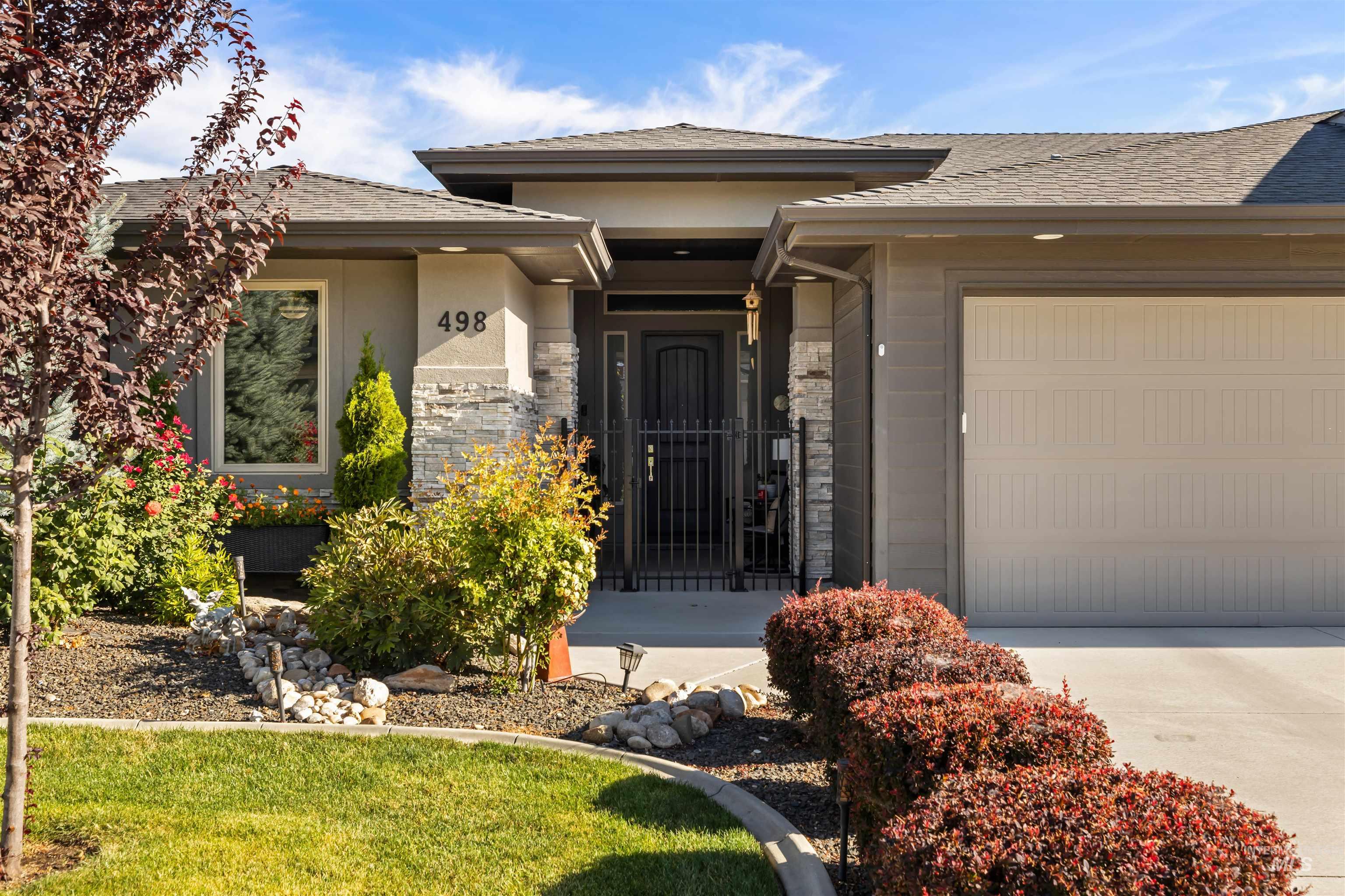 Property entrance with an attached garage, stone siding, concrete driveway, a shingled roof, and stucco siding