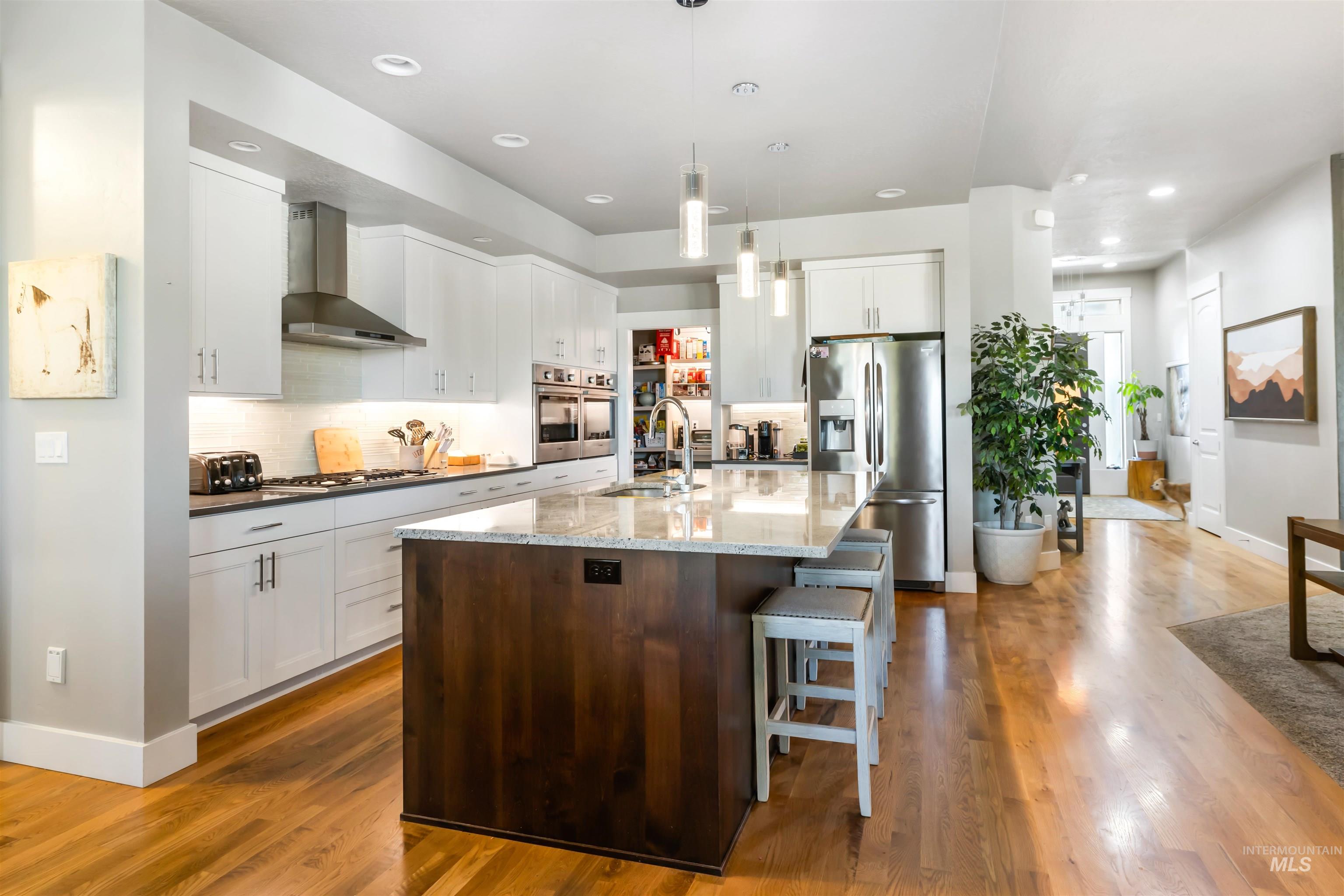 Kitchen featuring pendant lighting, white cabinets, tasteful backsplash, stainless steel fridge with ice dispenser, and recessed lighting