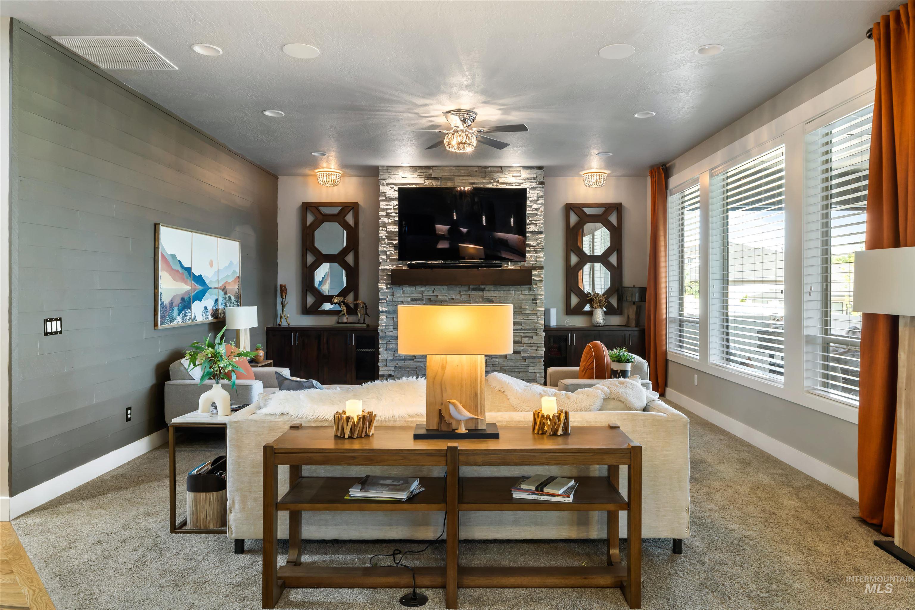 Carpeted living area featuring a fireplace and ceiling fan