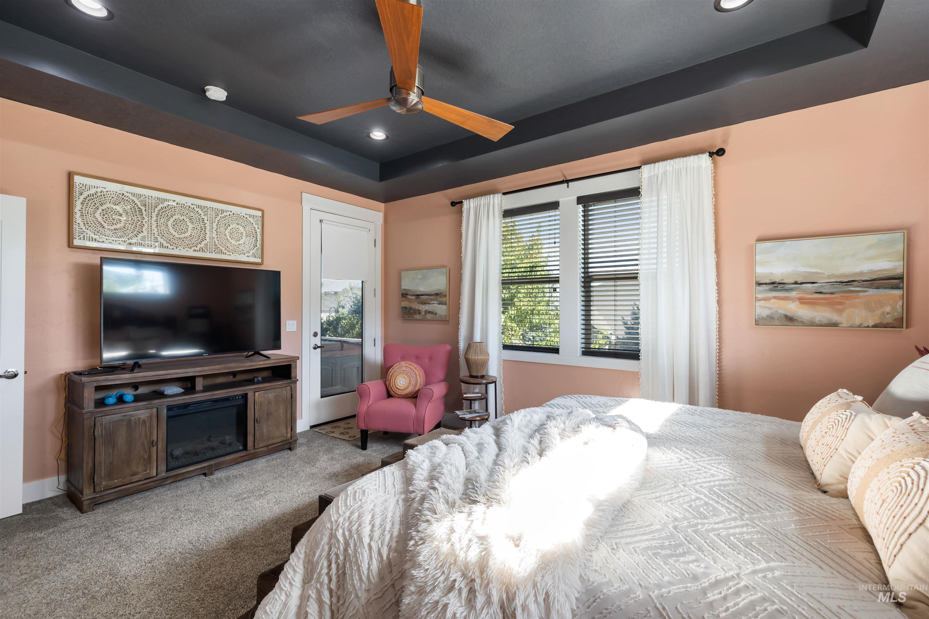 Bedroom featuring a raised ceiling, access to exterior, recessed lighting, carpet, and ceiling fan