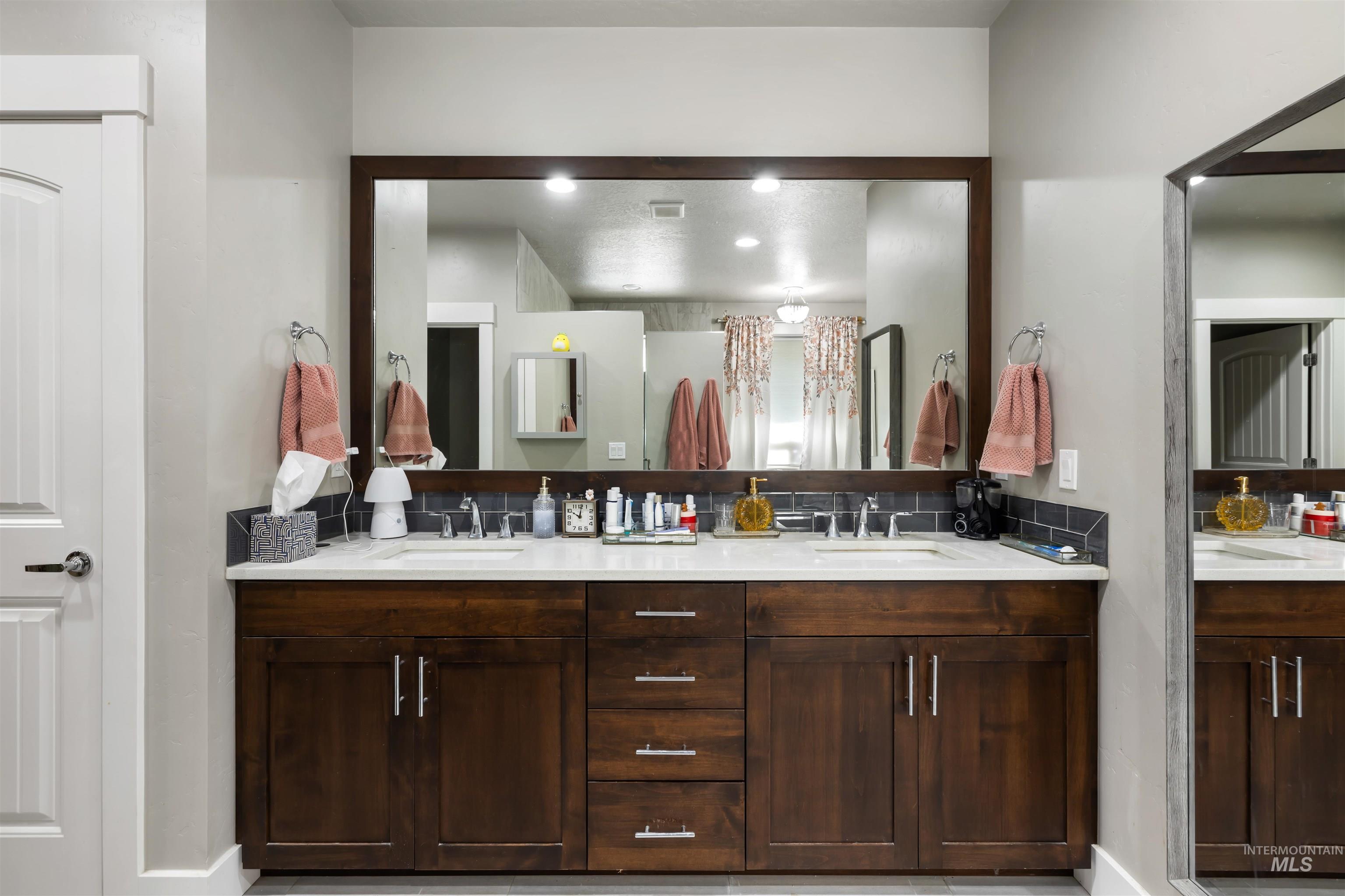 Full bath featuring decorative backsplash and double vanity
