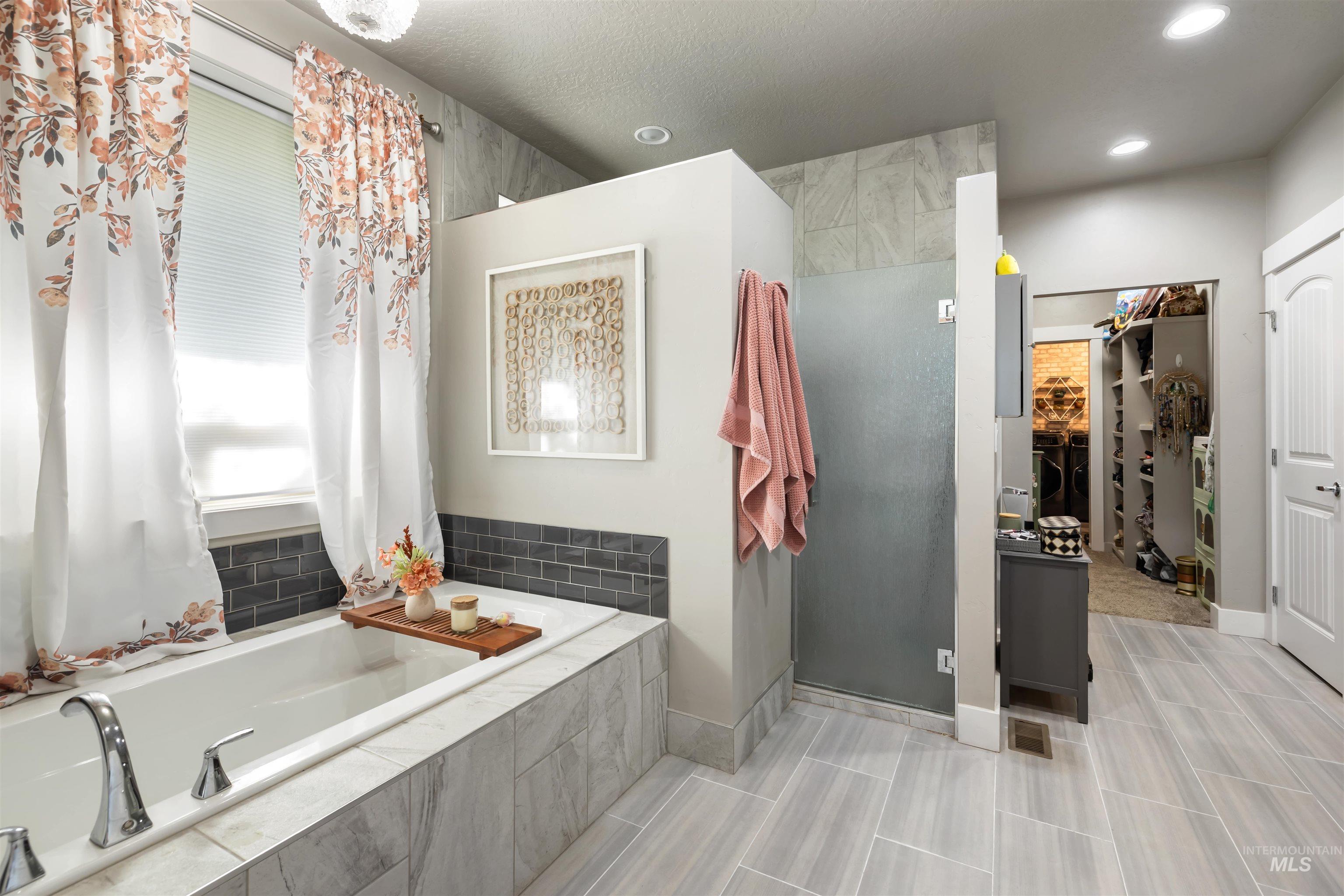 Bathroom with a walk in closet, a garden tub, a stall shower, and recessed lighting