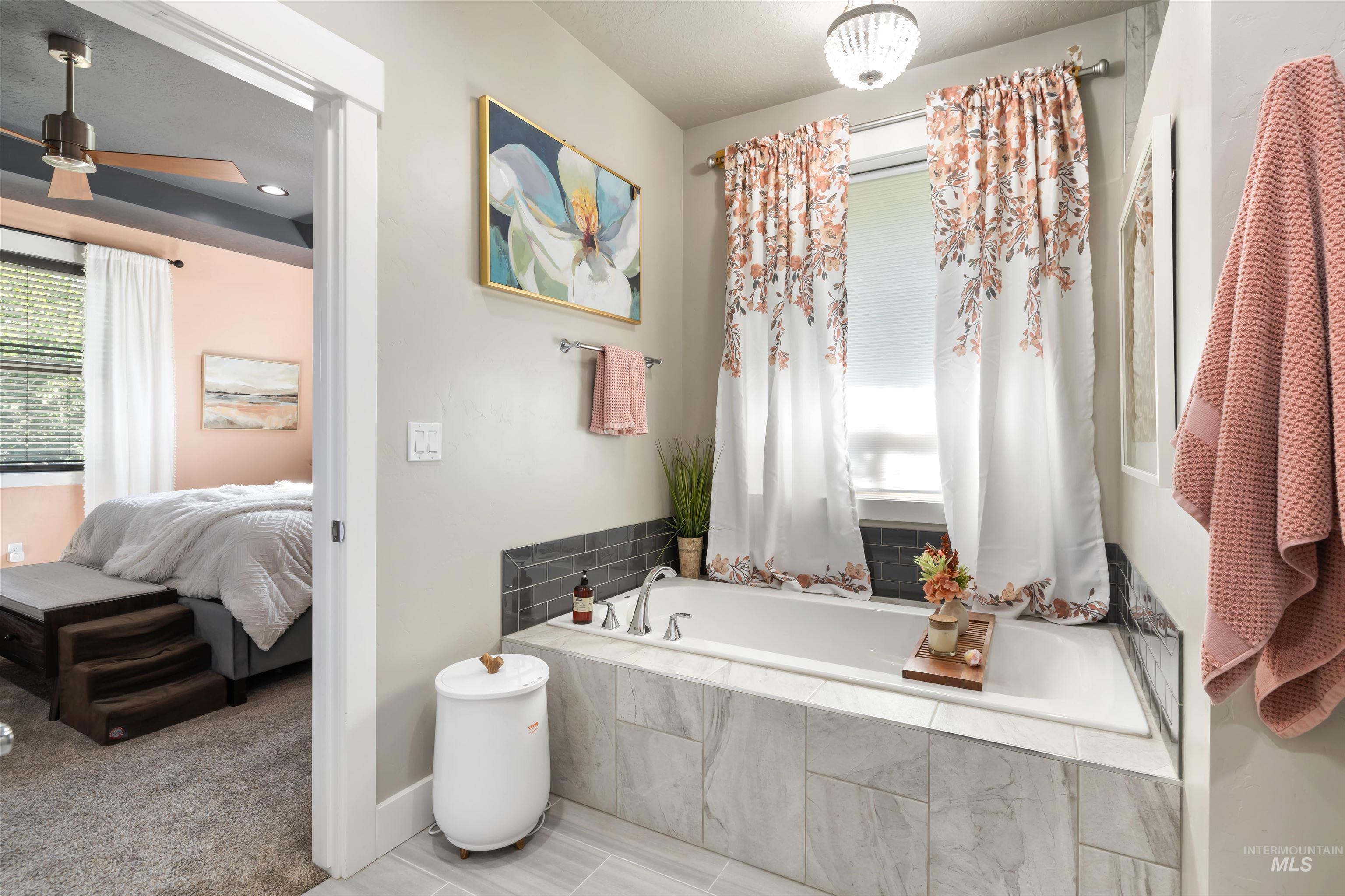 Ensuite bathroom with a garden tub, a textured ceiling, and tile patterned flooring