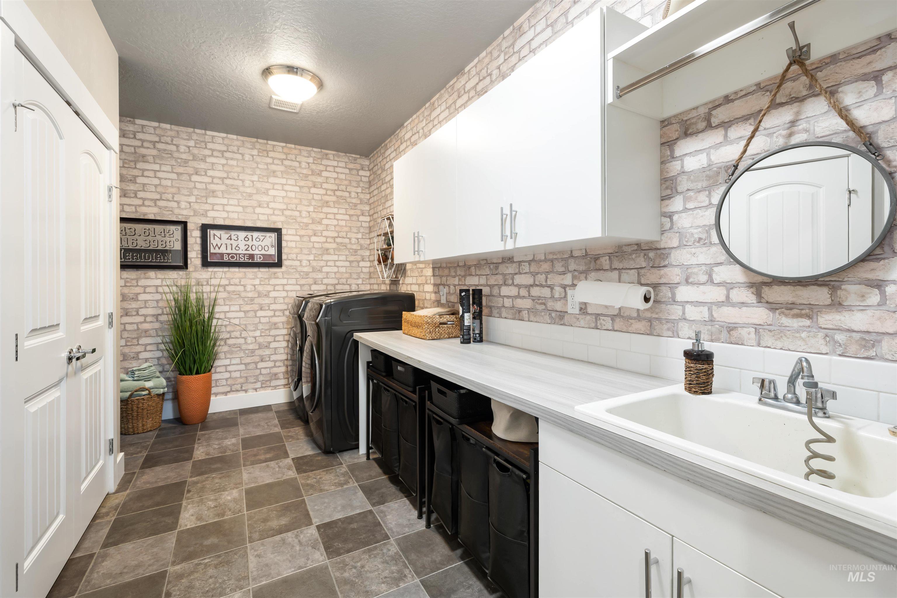 Kitchen featuring white cabinetry, light countertops, a textured ceiling, washing machine and dryer, and stone finish floors