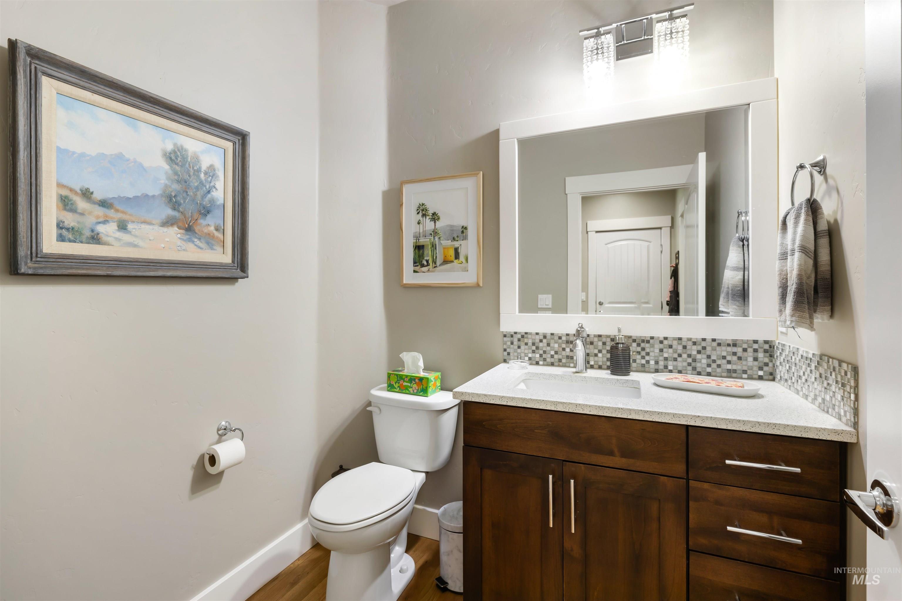 Half bathroom with vanity, decorative backsplash, and light wood finished floors