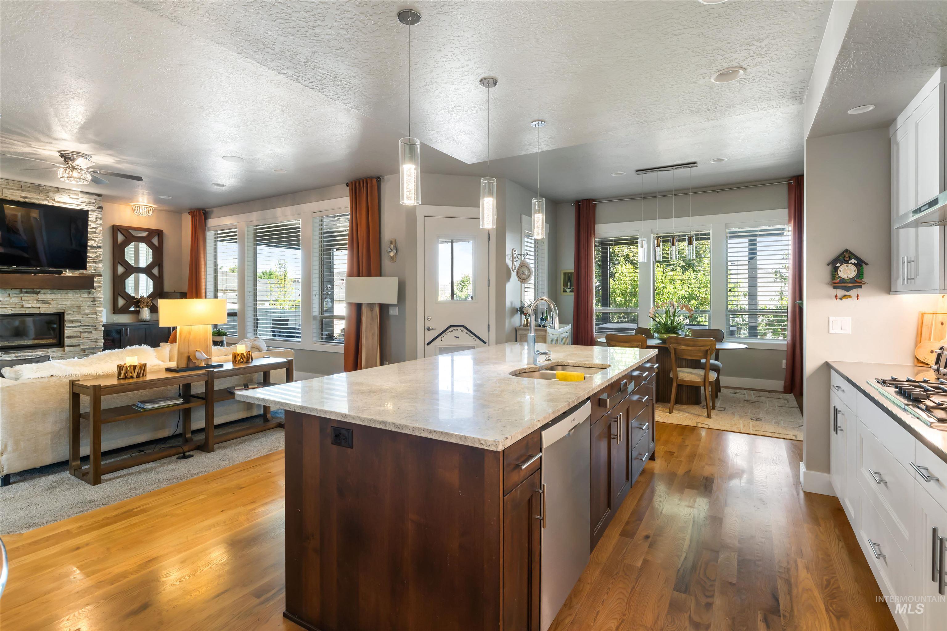 Kitchen with a textured ceiling, dark wood-style floors, white cabinetry, decorative light fixtures, and dark brown cabinetry